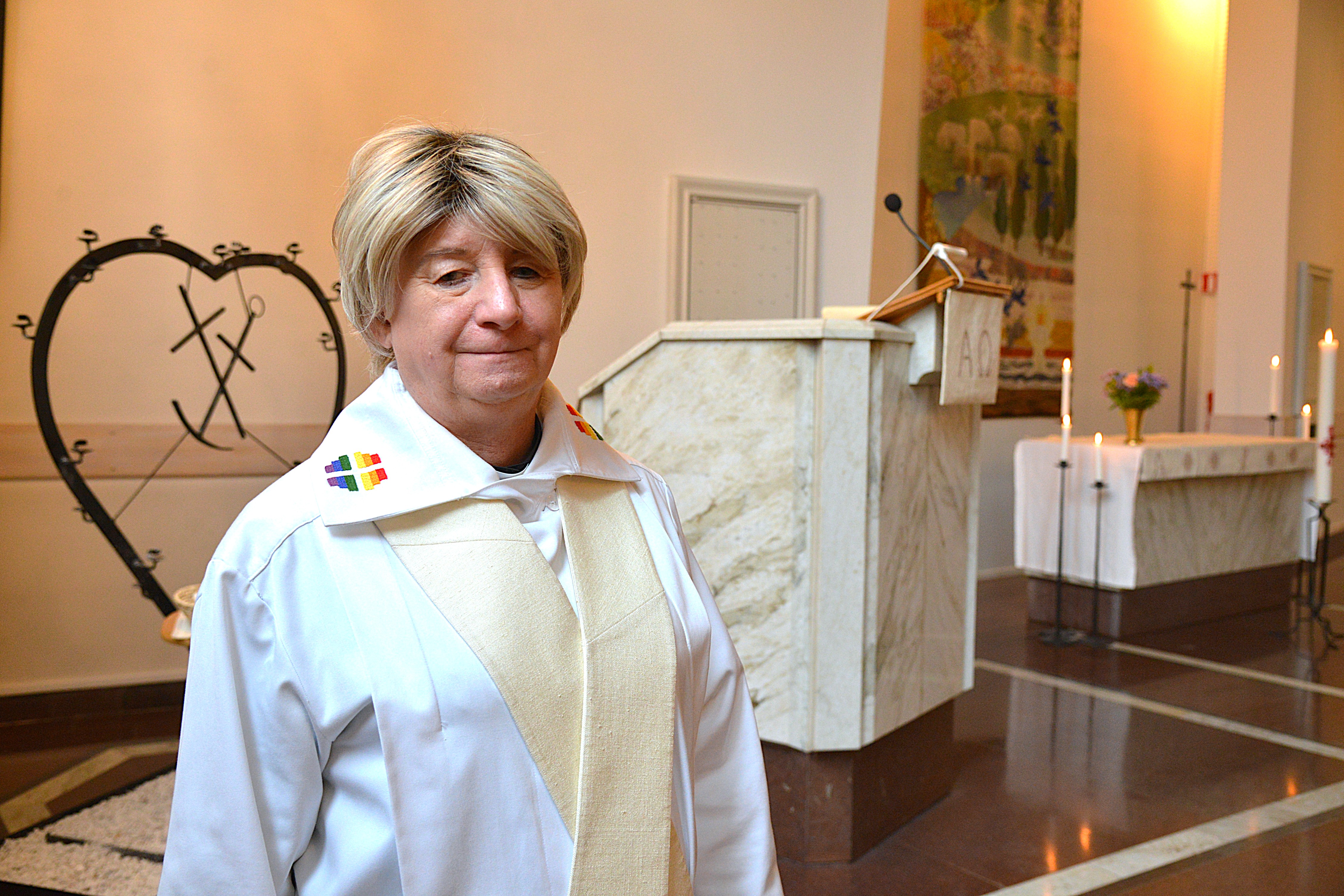 En kvinna står prästklädd i ett kyrkorum
