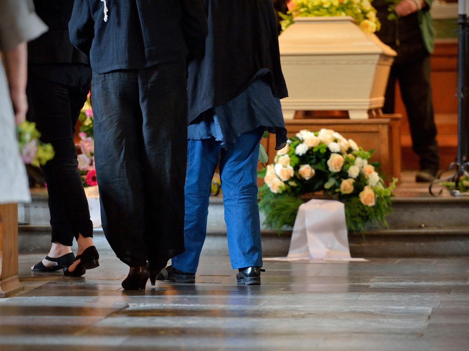 Två par ben ses gående mot en kista i en kyrka