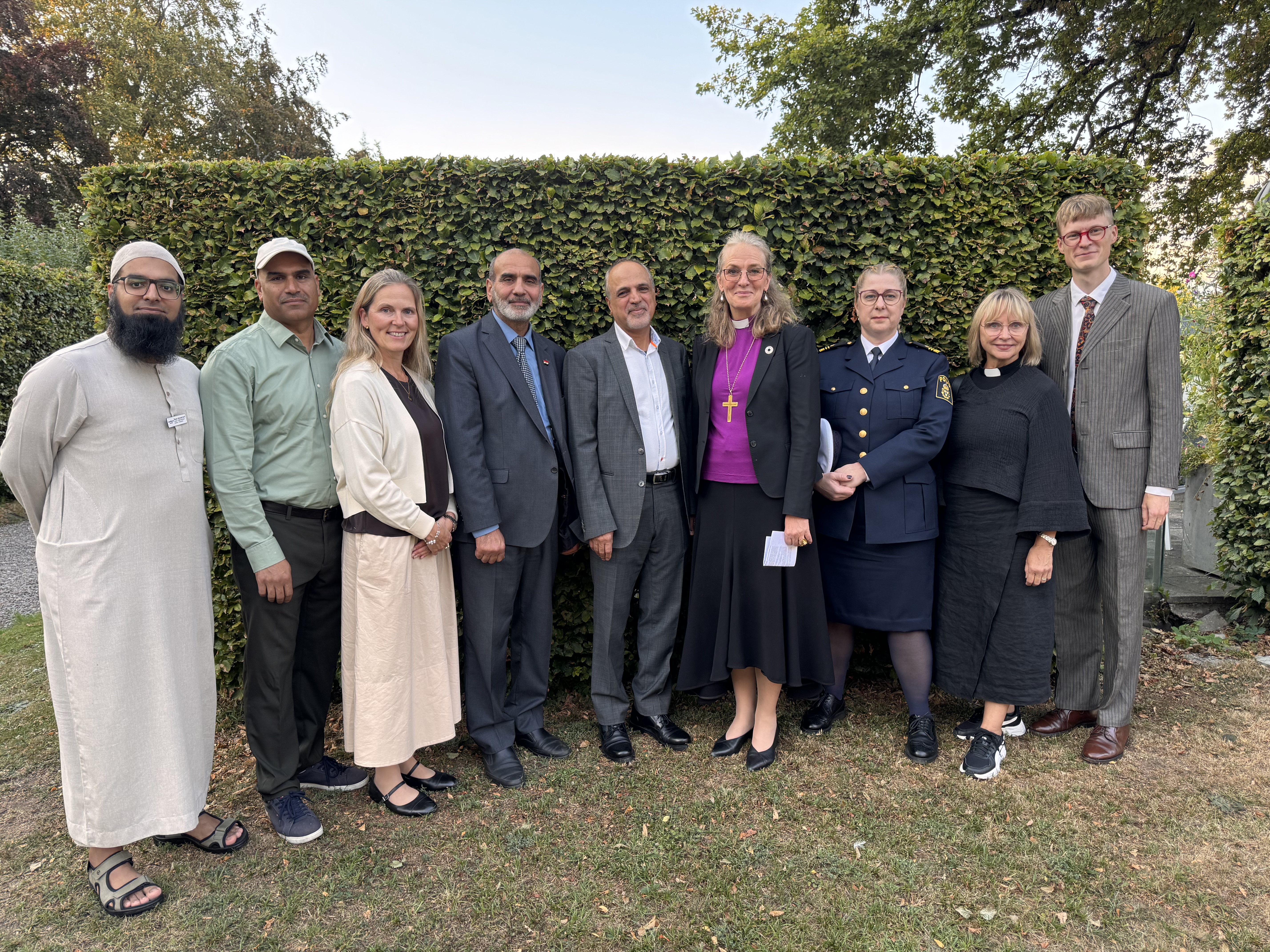 Några av kvällens representanter i gruppbild framför en häck i biskopsgårdens trädgård
