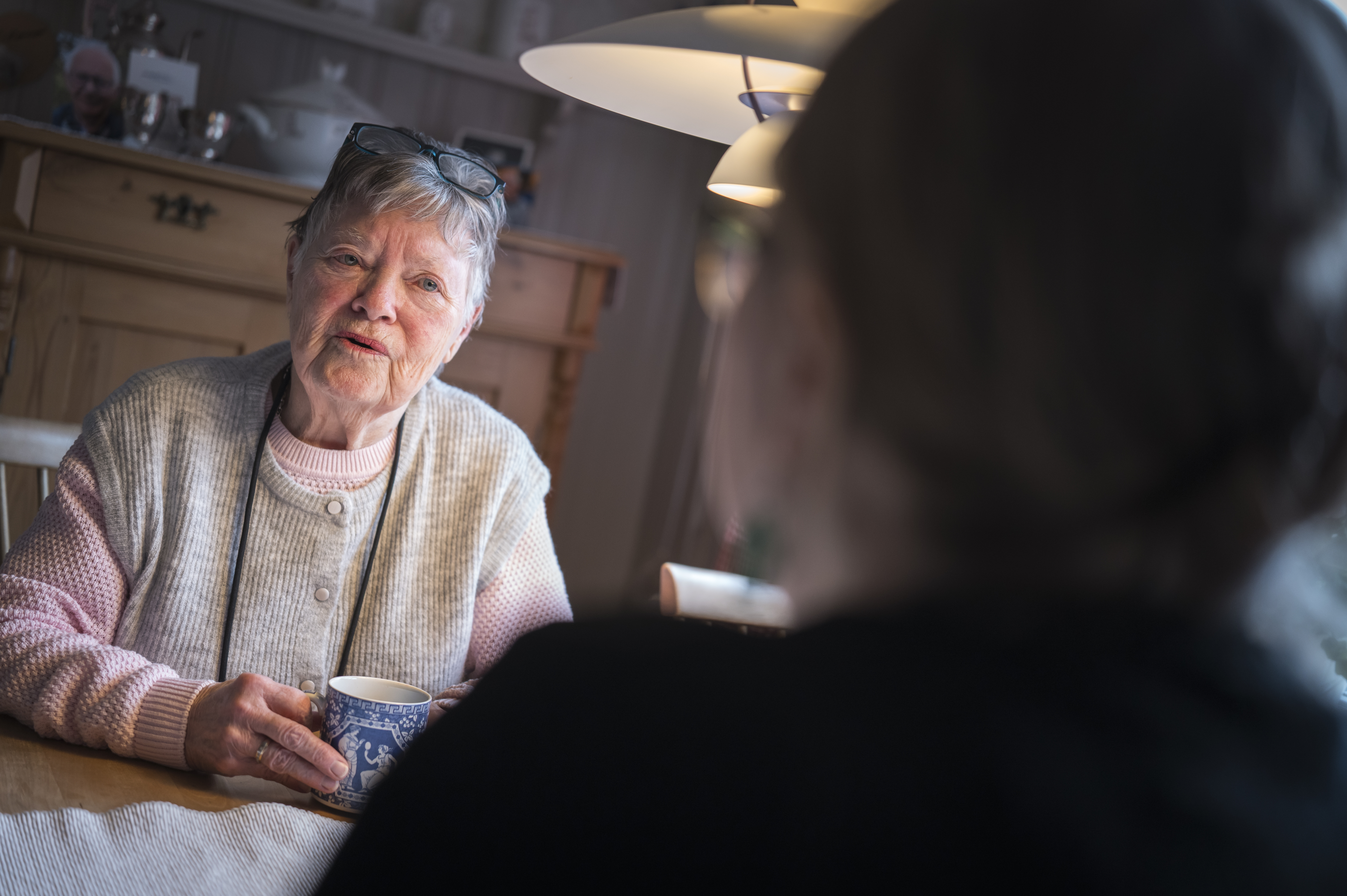 Två personer sitter och samtalar över en kopp kaffe