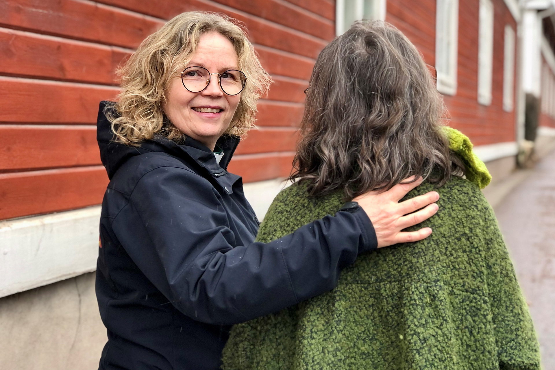 En diakon håller armarna om en församlingsbo