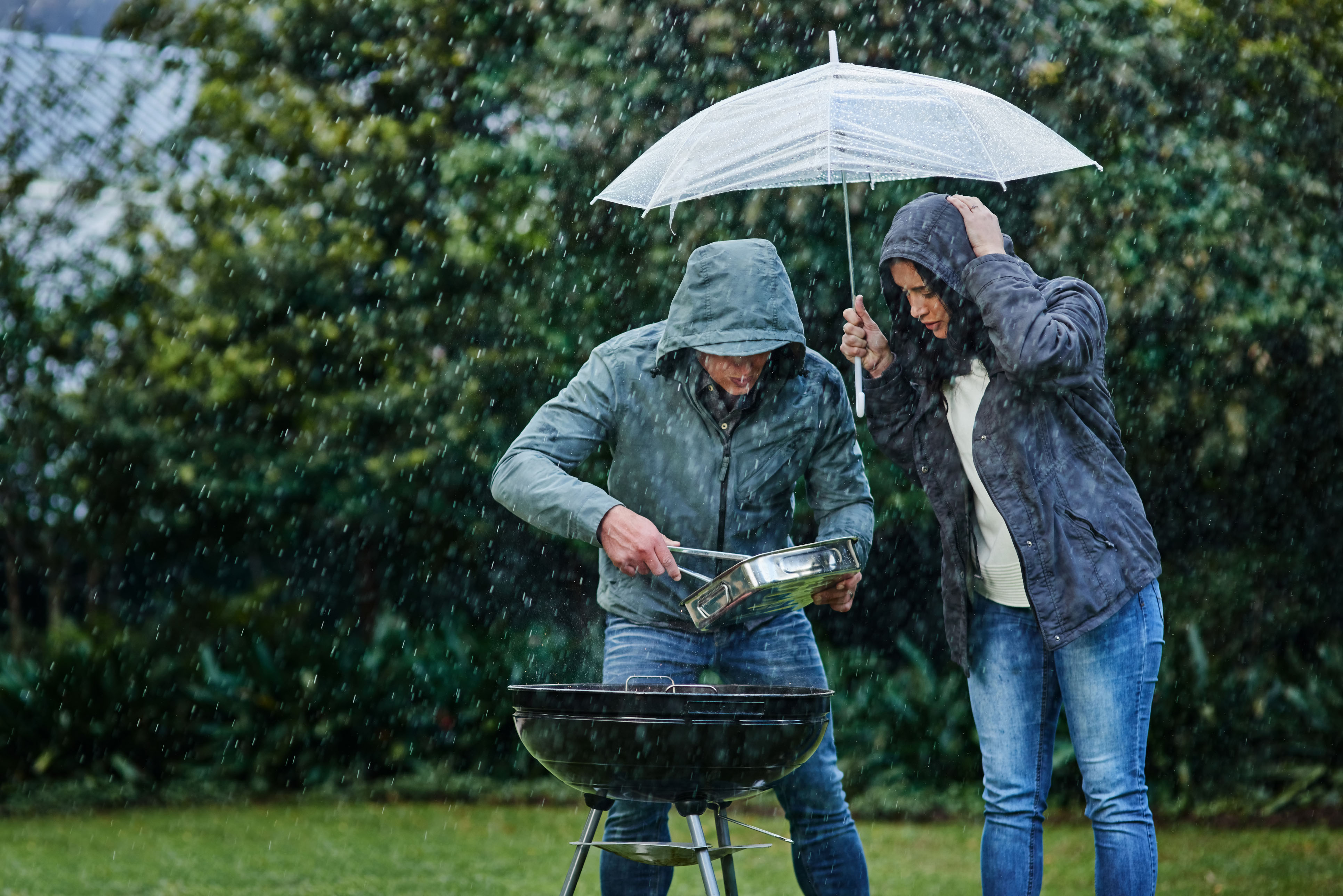 Ett par som försöker tända grillen i regn.