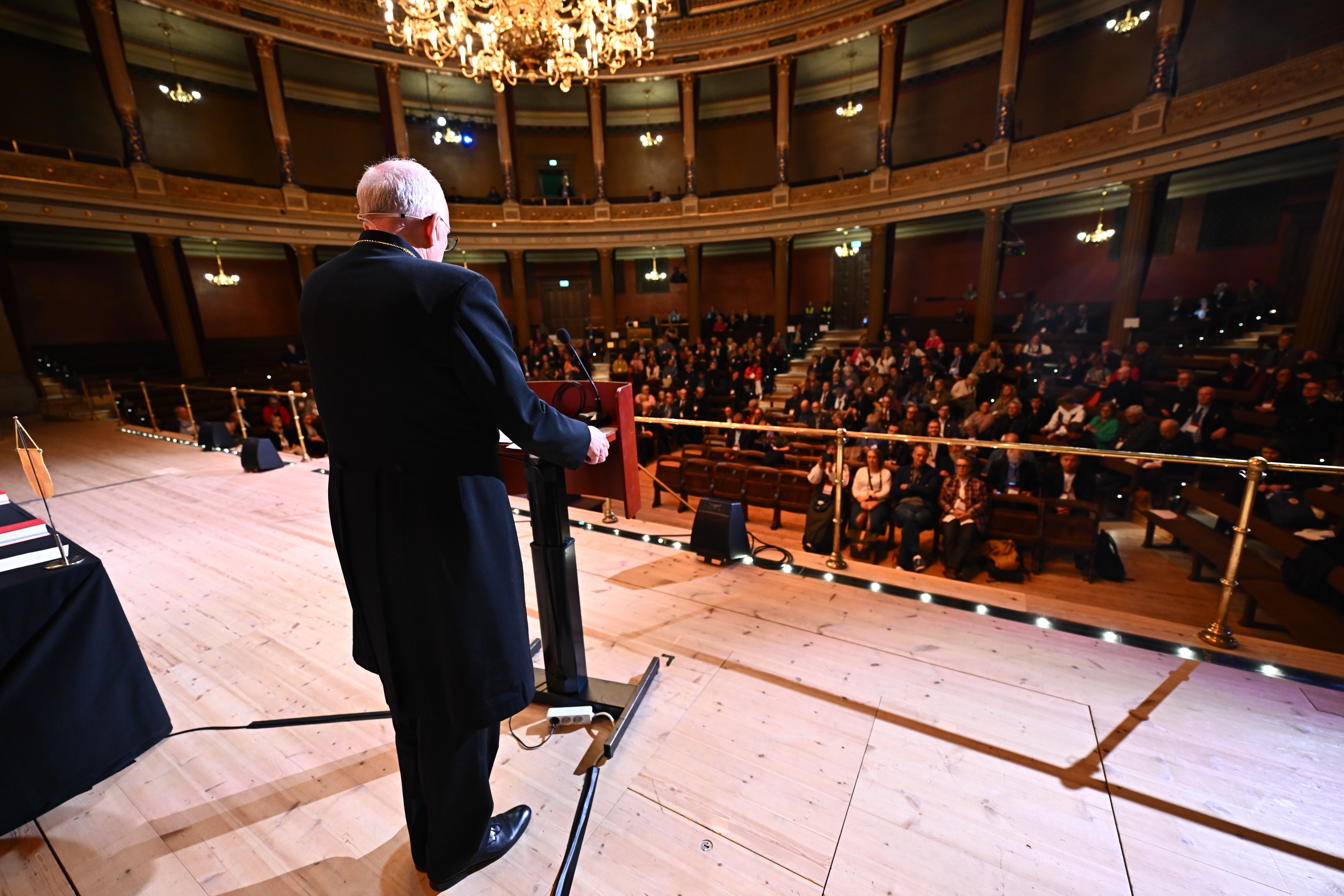 Ärkebiskop Martin står vid en talarstol och ser över en fullsatt sal.