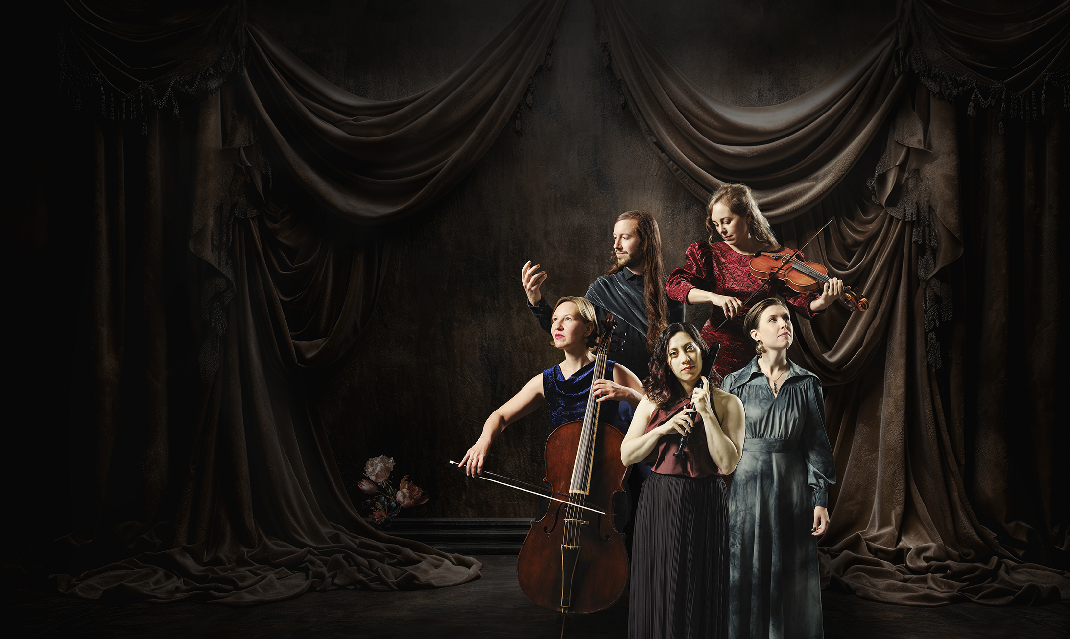 Grupp om fem personer med bland annat cello, flöjt och violin. Mörk bakgrund.