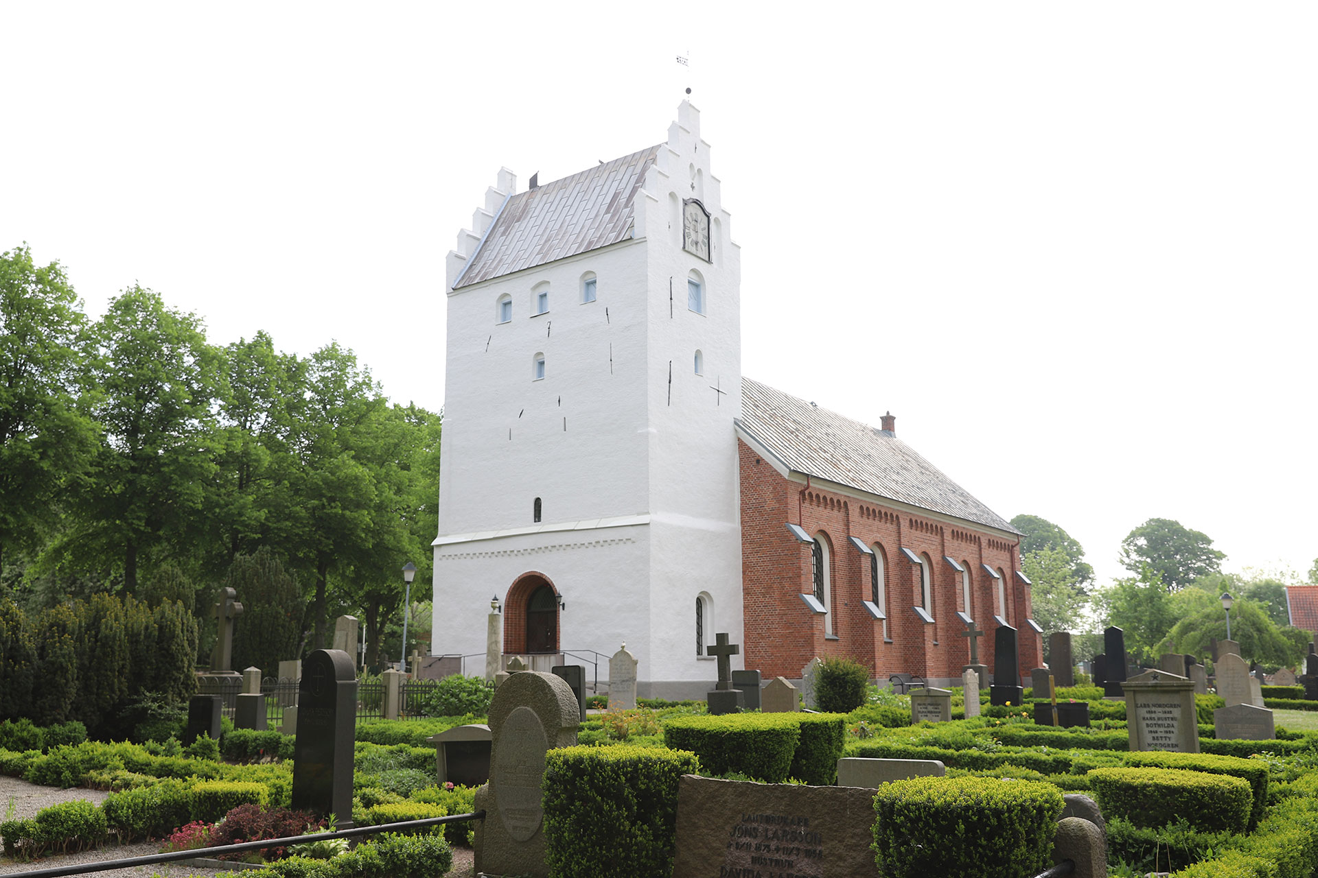 Vitt kyrktorn och ett huvudskepp i rött tegel.