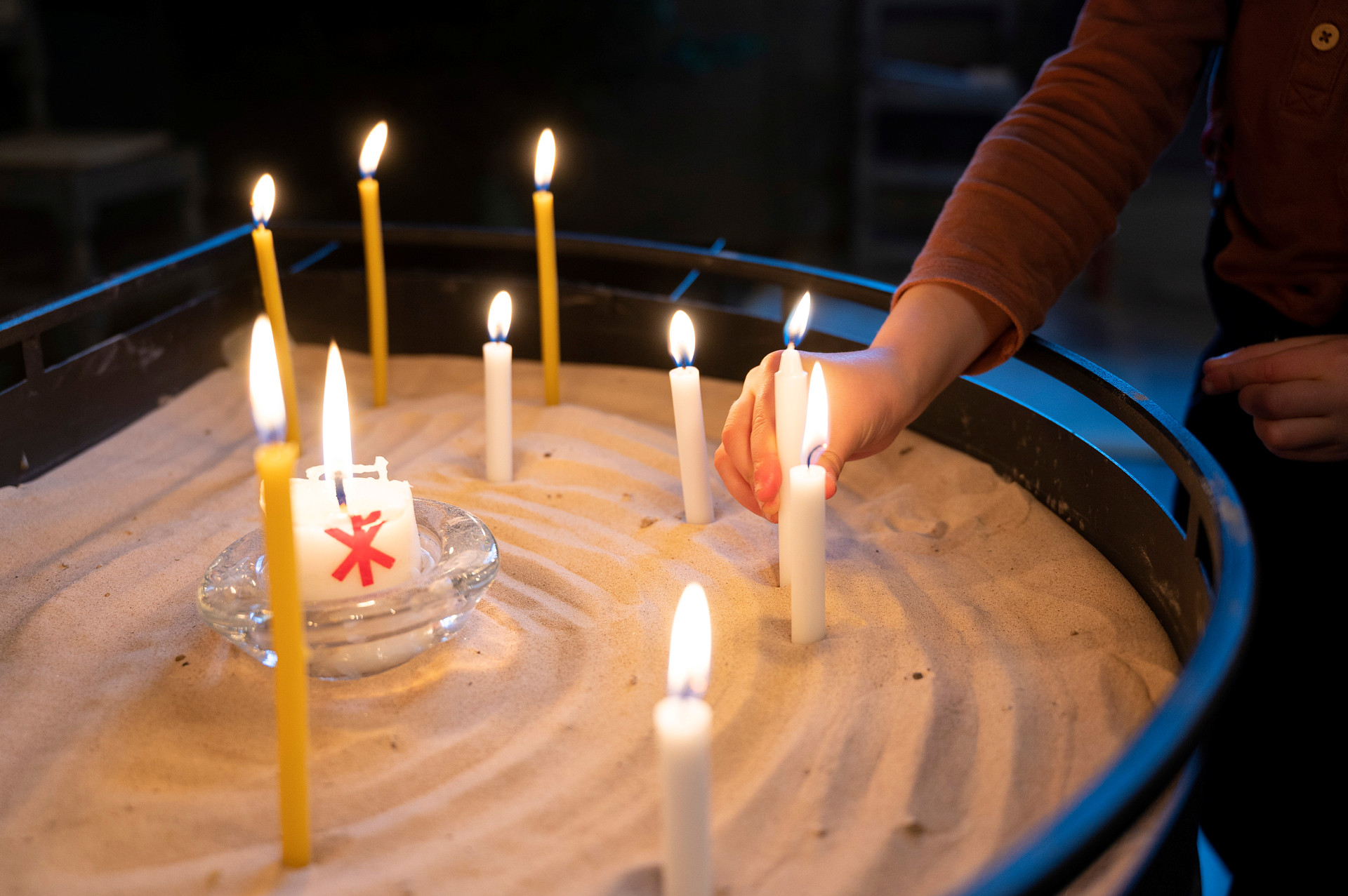 Sand med instuckna ljus som är tända.