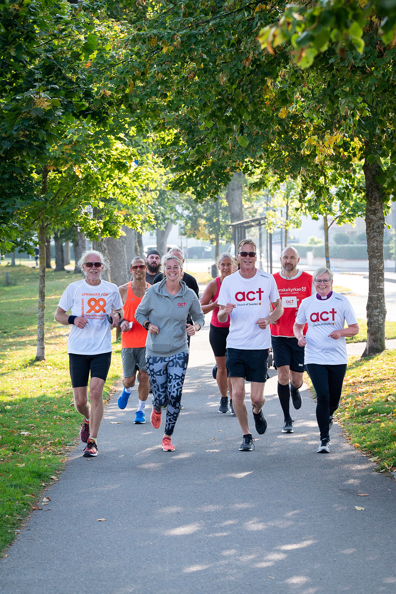 En grupp glada människor springer tillsammans på en väg.