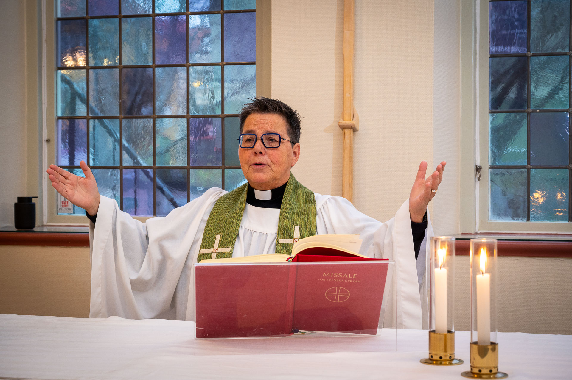 En kvinnlig präst läser välsignelsen över församlingen.