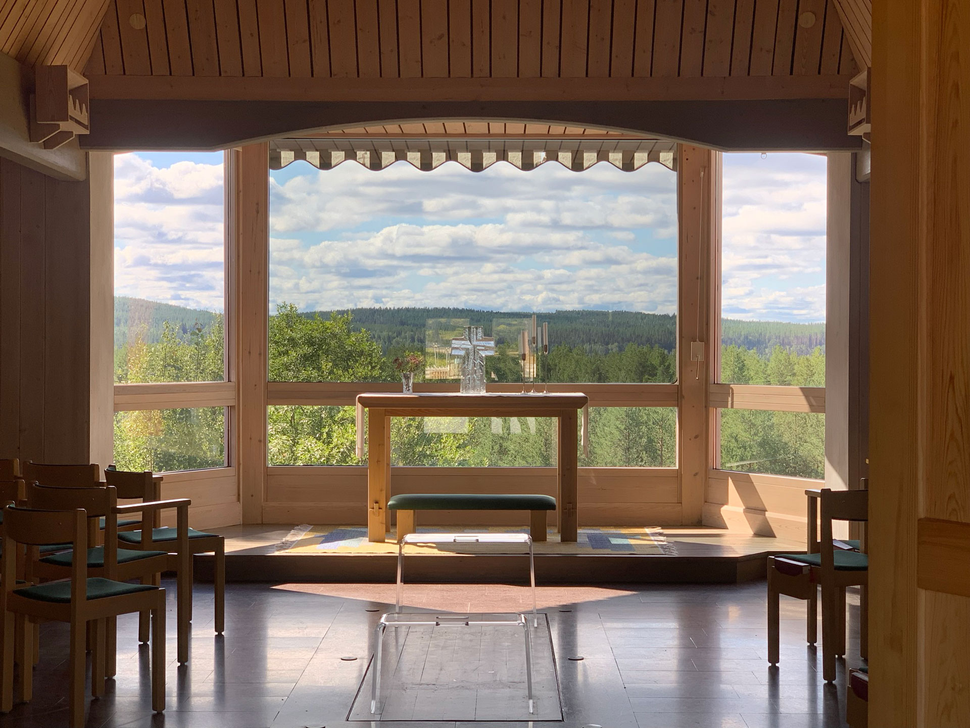 Interiörbild från Mariakapellet i Junsele. Bakom altaret ser vi ut genom stora fönster. Skog och himmel utgör på så sätt "altartavla".