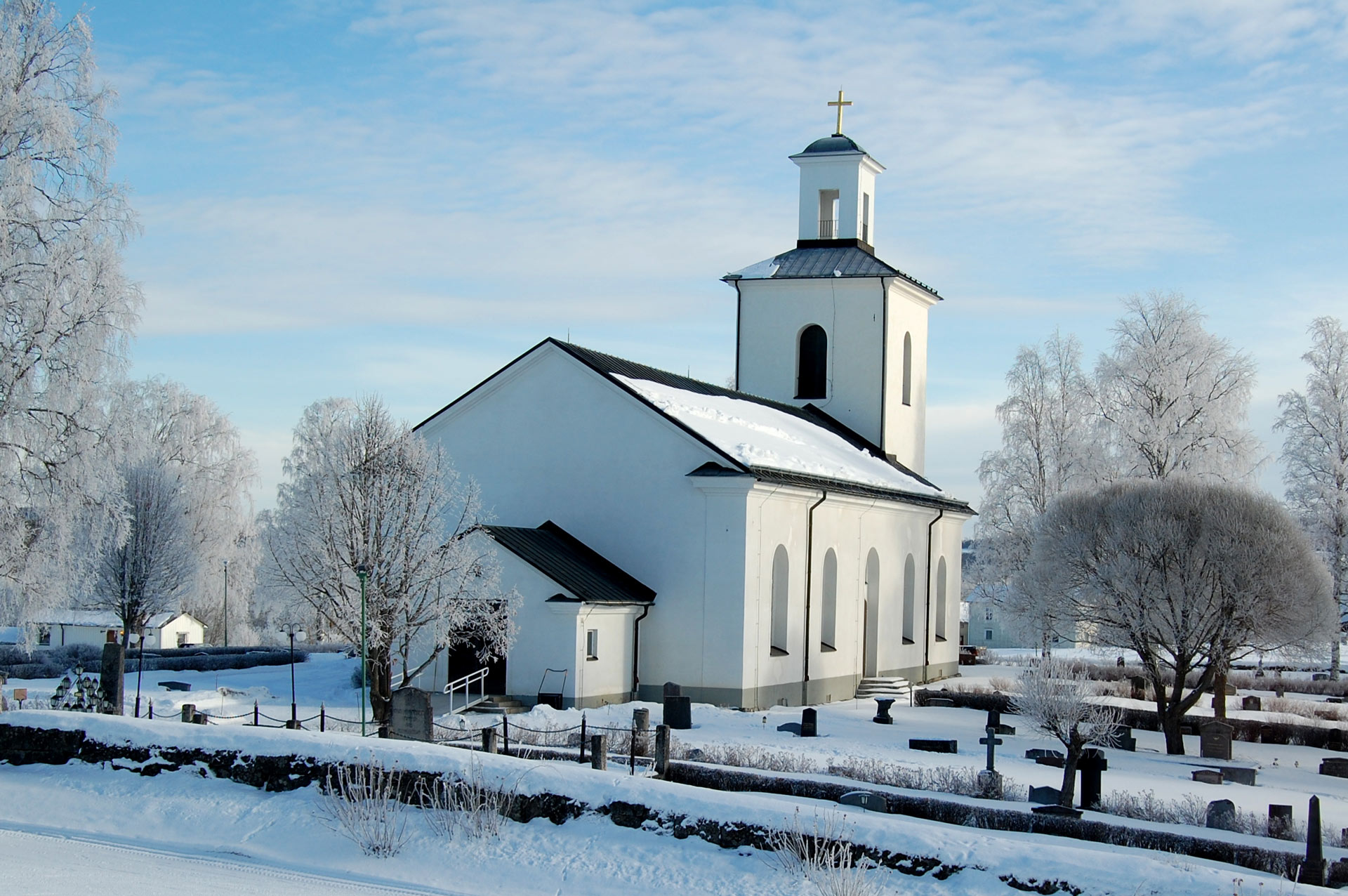Långsele kyrka samt delar av kyrkogården. Det är vinter och frosten klär träden.
