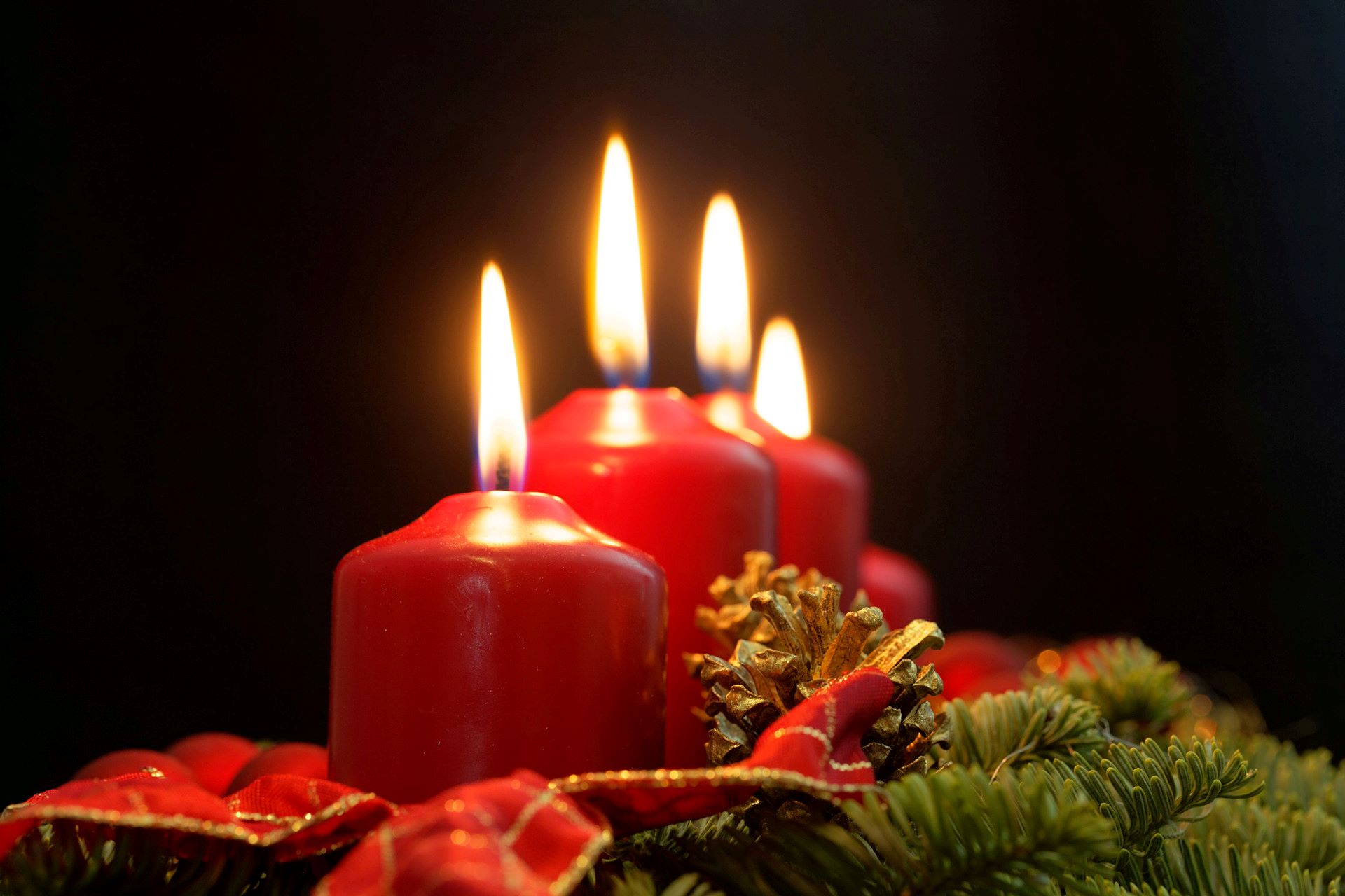  Fyra röda blockljus brinner i en adventsljusstake.