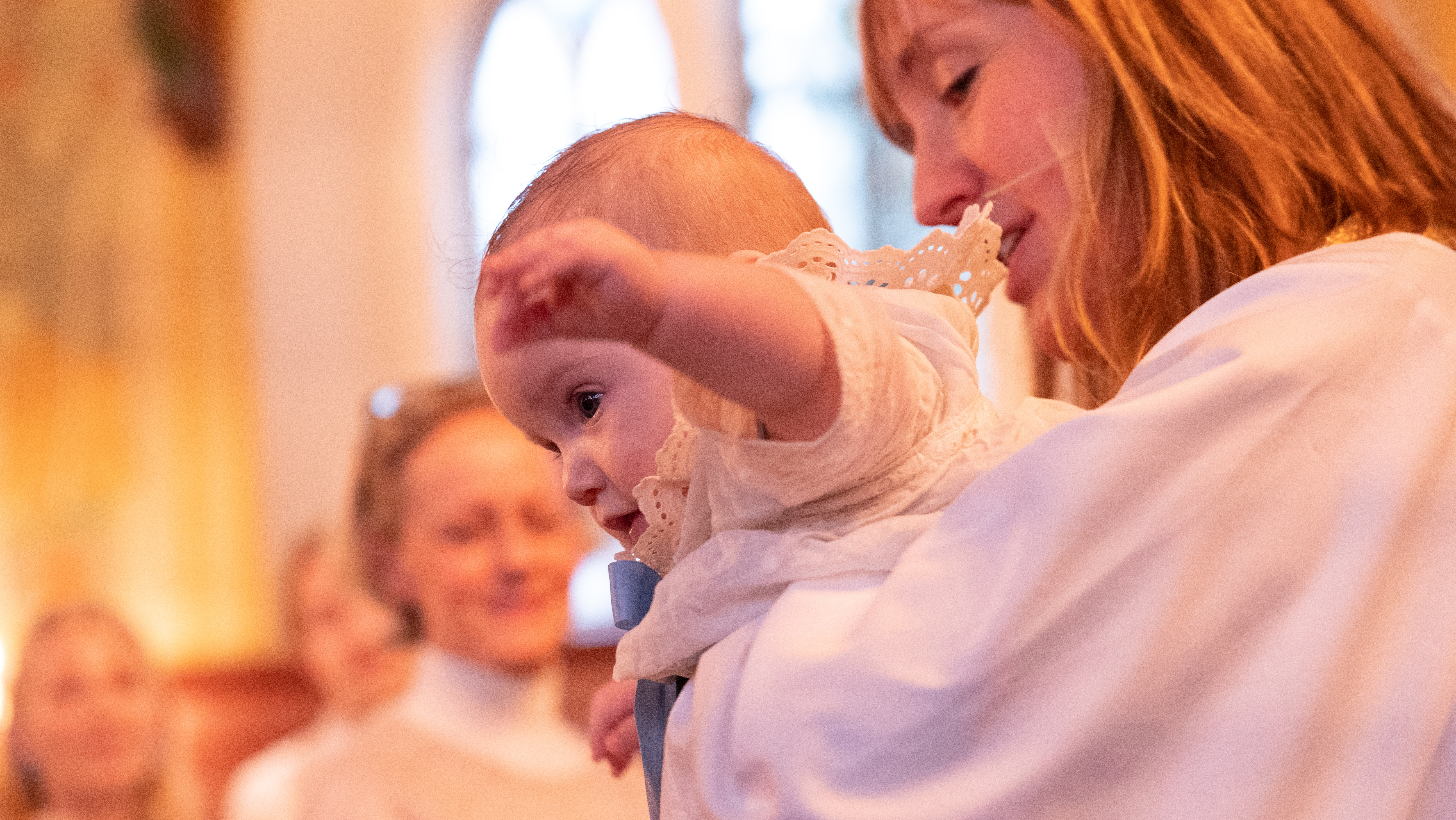 En präst som håller ett barn inför dop.