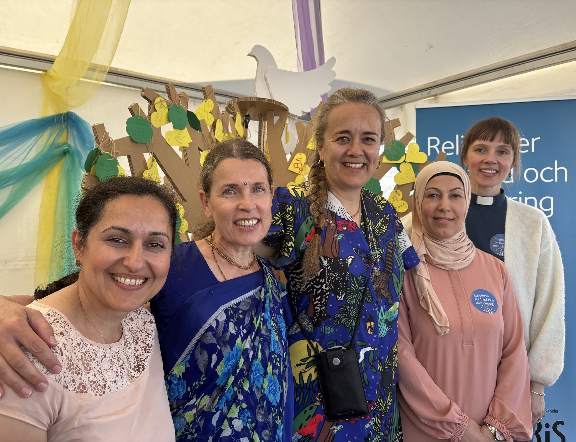 Gruppbild på fem leende kvinnor i olika religiösa kläder från en tidigare upplaga av Järvaveckan
