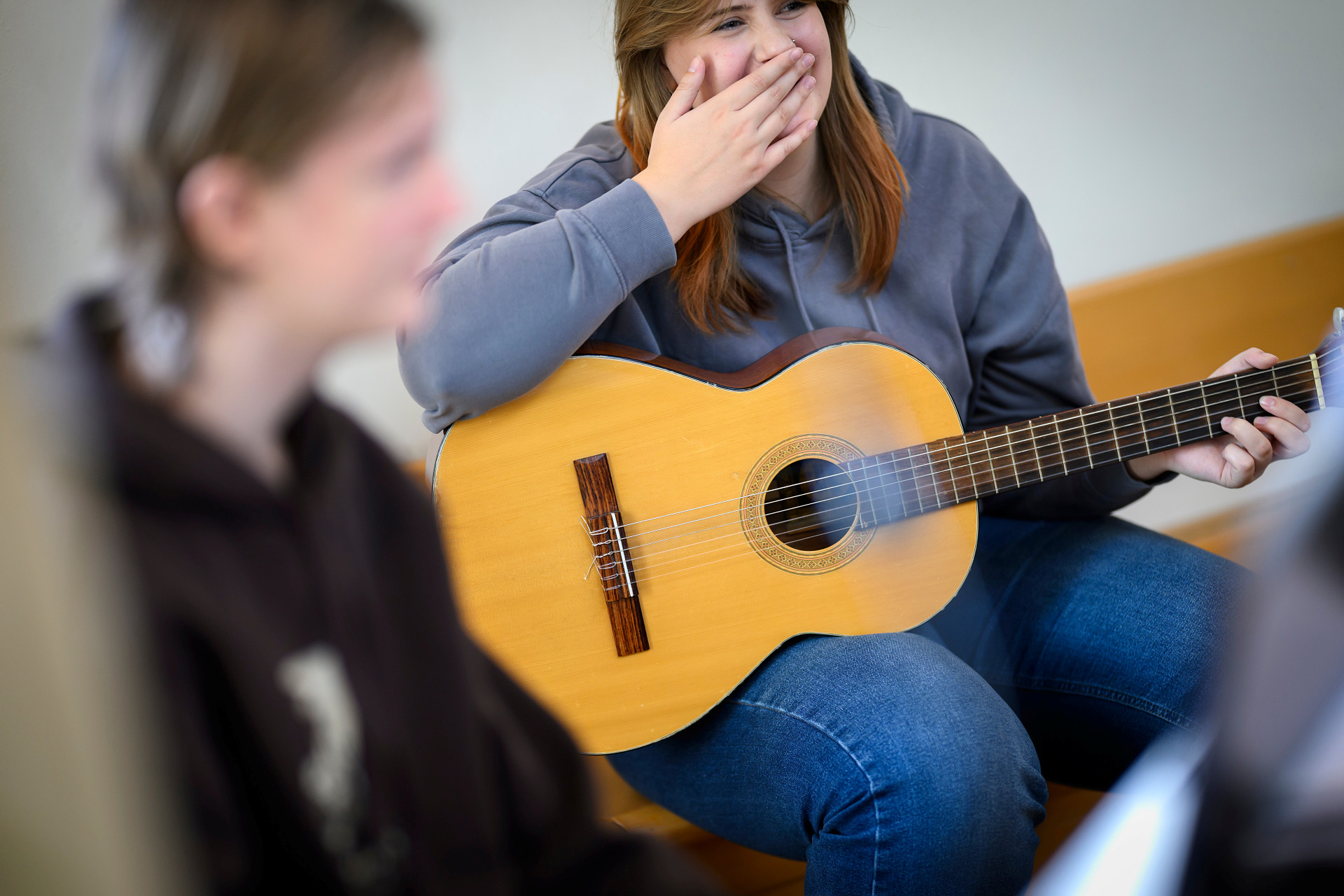 Ung tjej med gitarr i knät. Hon skrattar.