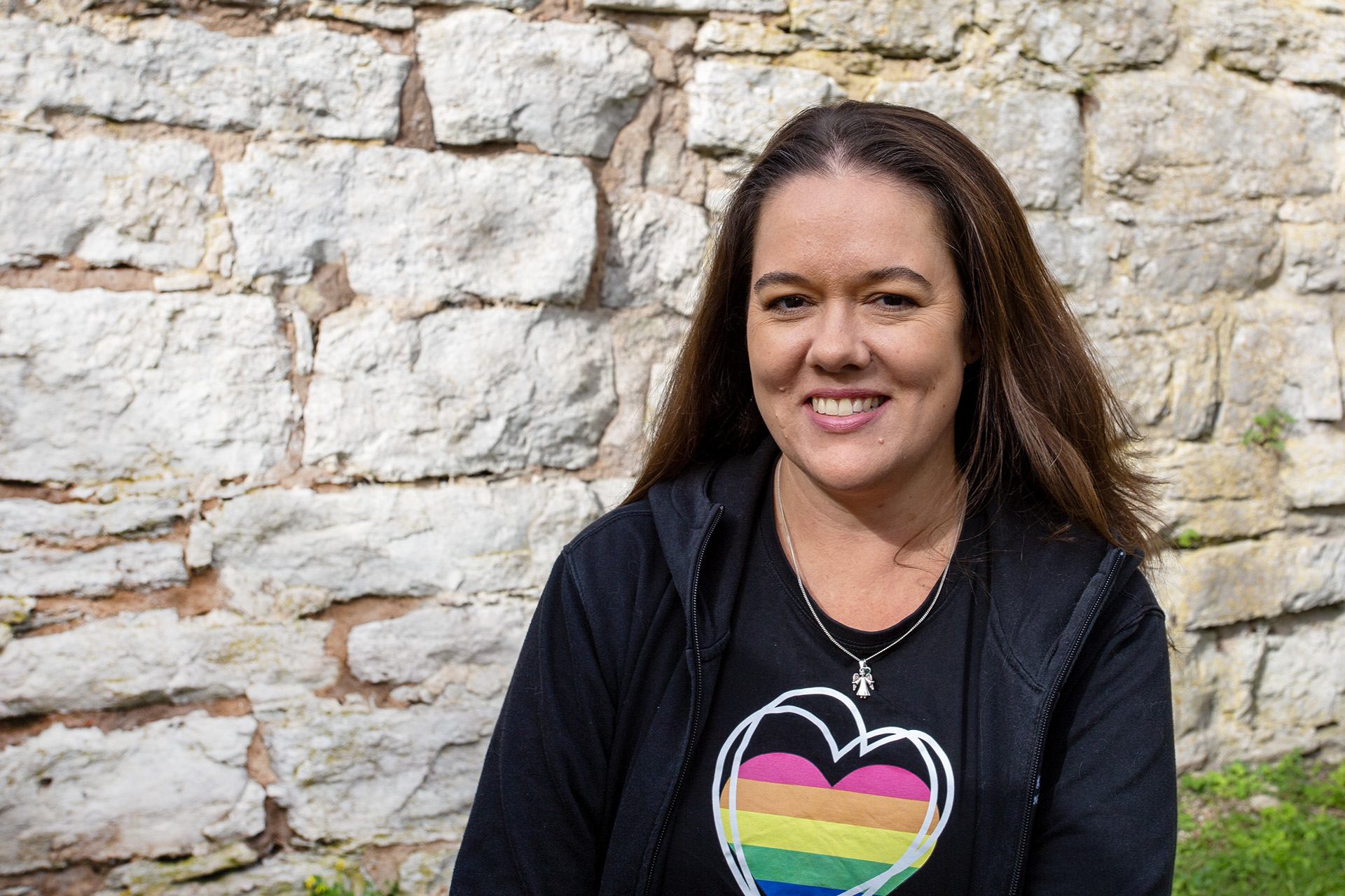 kvinna ler, mur i bakgrunden