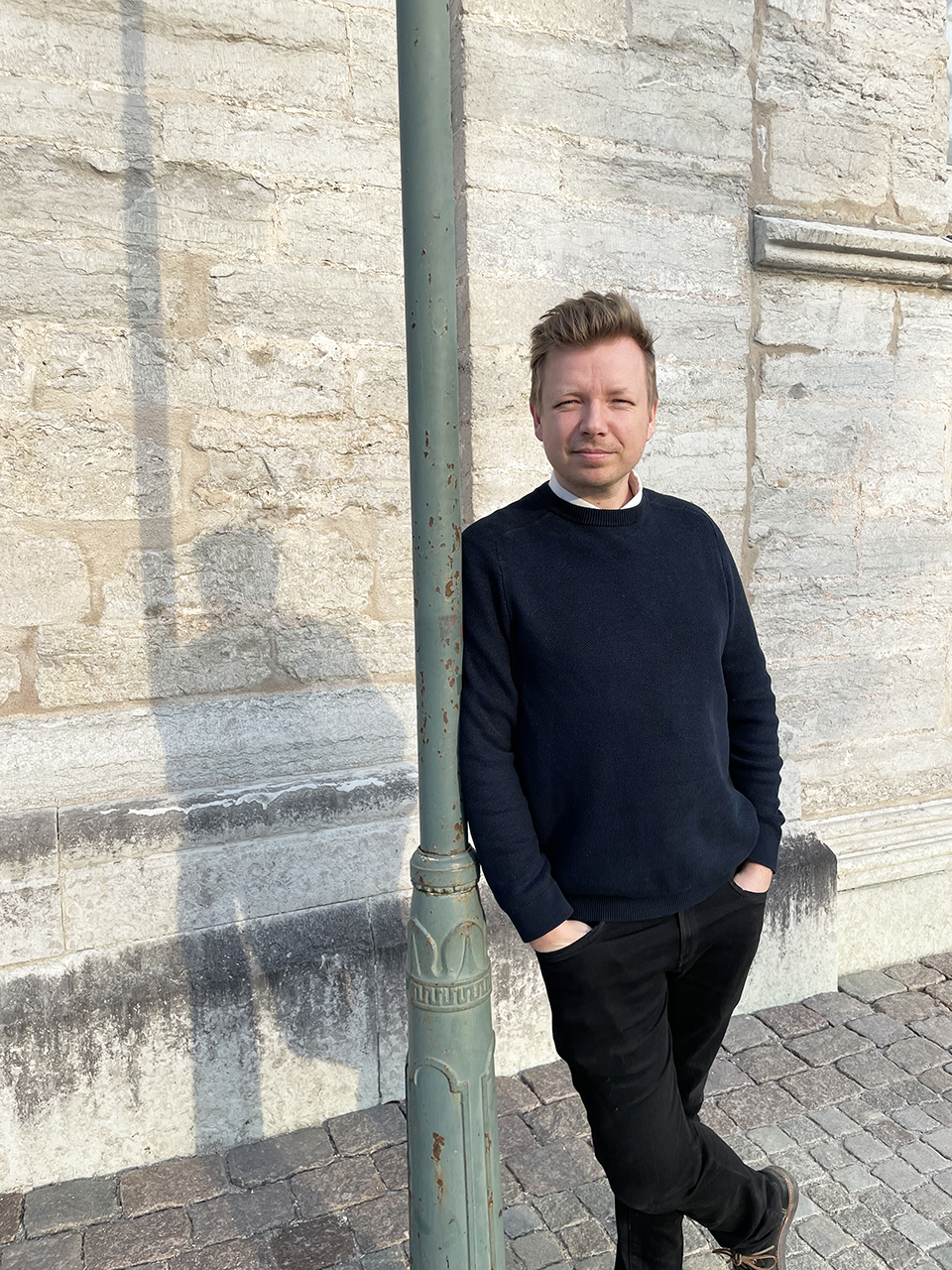 Person står och lutar sig mot lyktstolpe