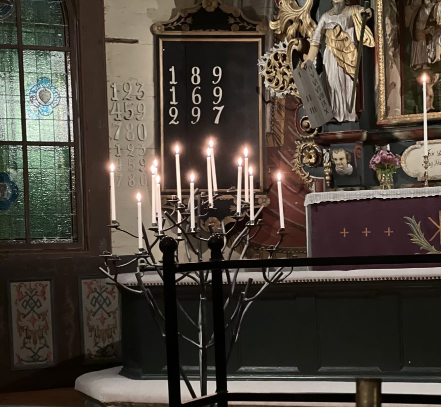 Några ljus brinner i ljusbäraren i Nysunds kyrka