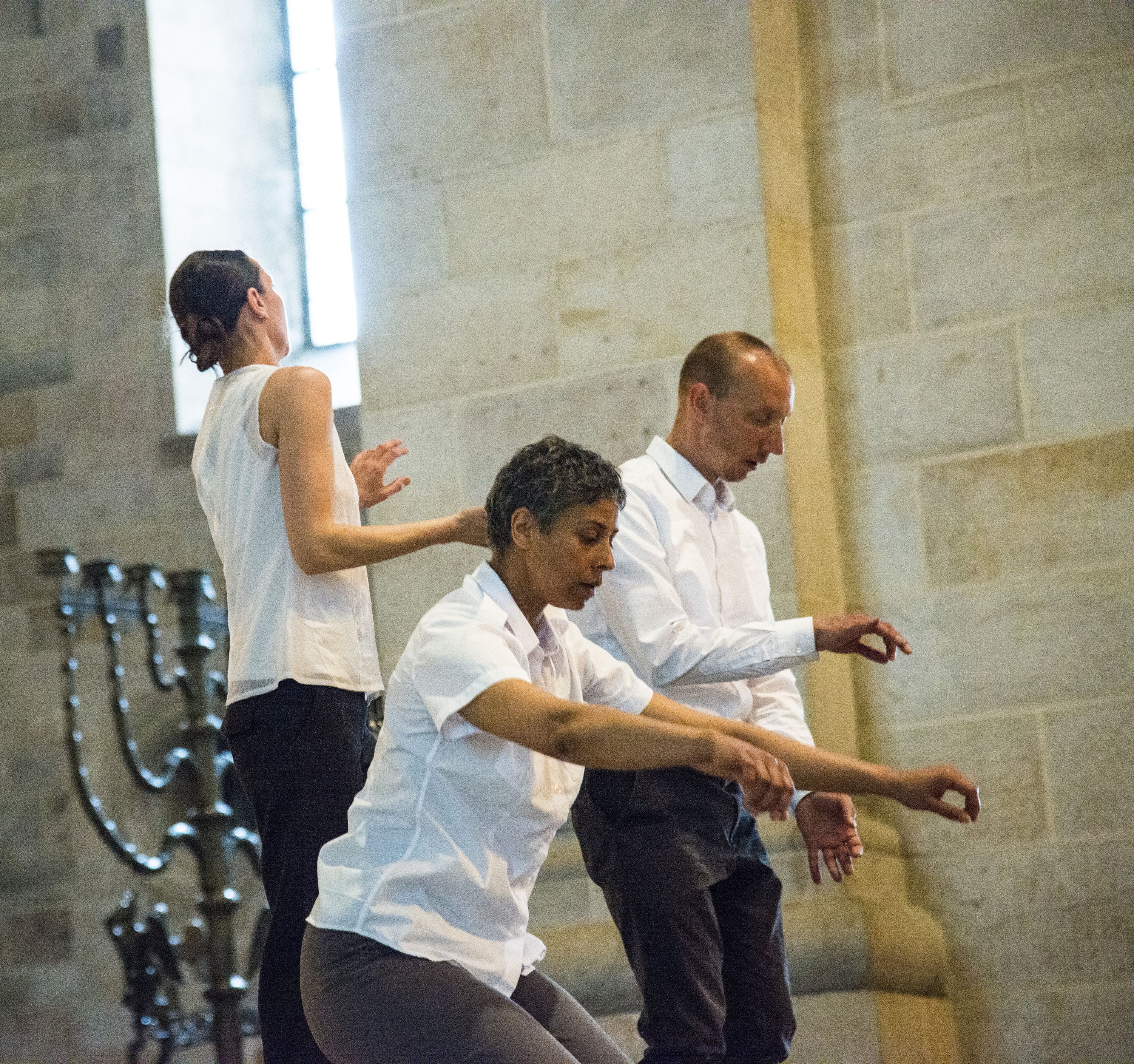Tre personer i vit överdel och svarta byxor dansar inne i Domkyrkan.