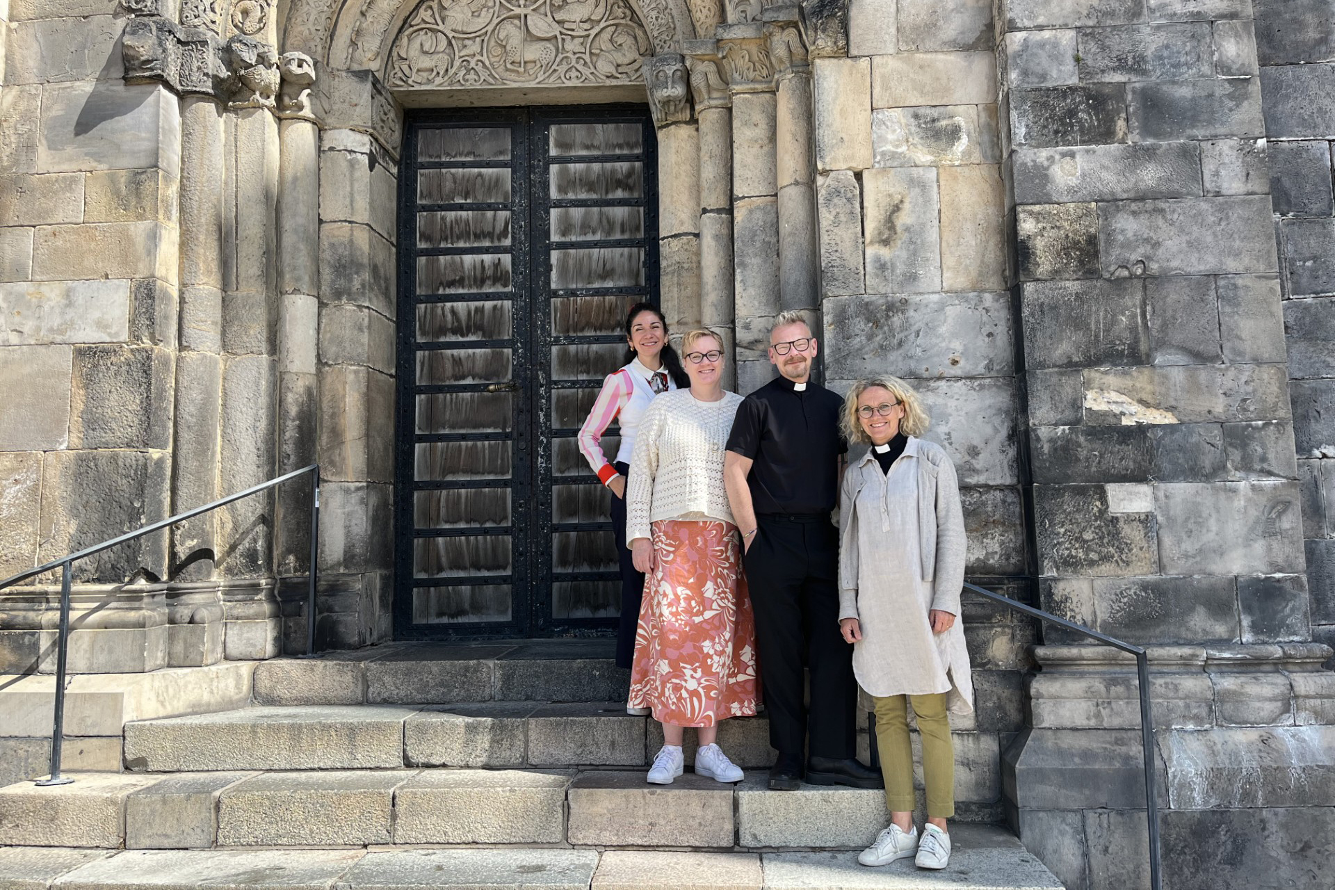 Fyra glada personer står framför Domkyrkans grå vägg av sten.