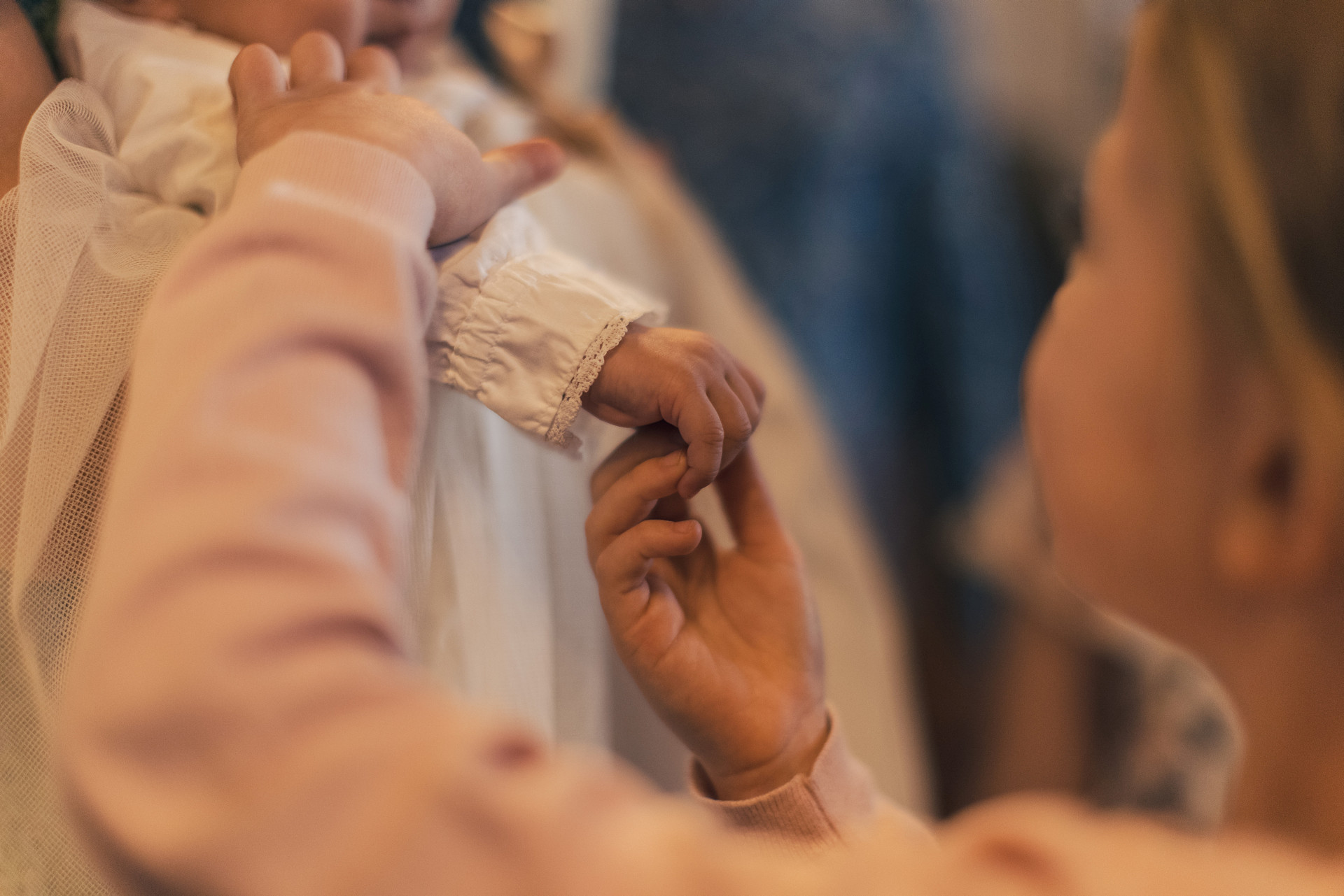 Dopbild där ett barns händer rör vid den lilla som ska döpas