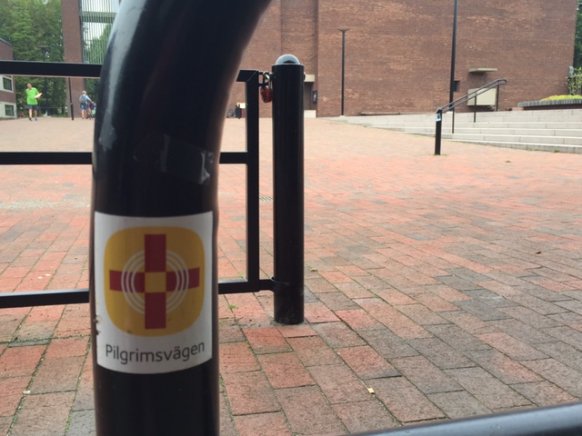 Stolpe med pilgrimsmärke för pilgrimsvägen på kyrktorget