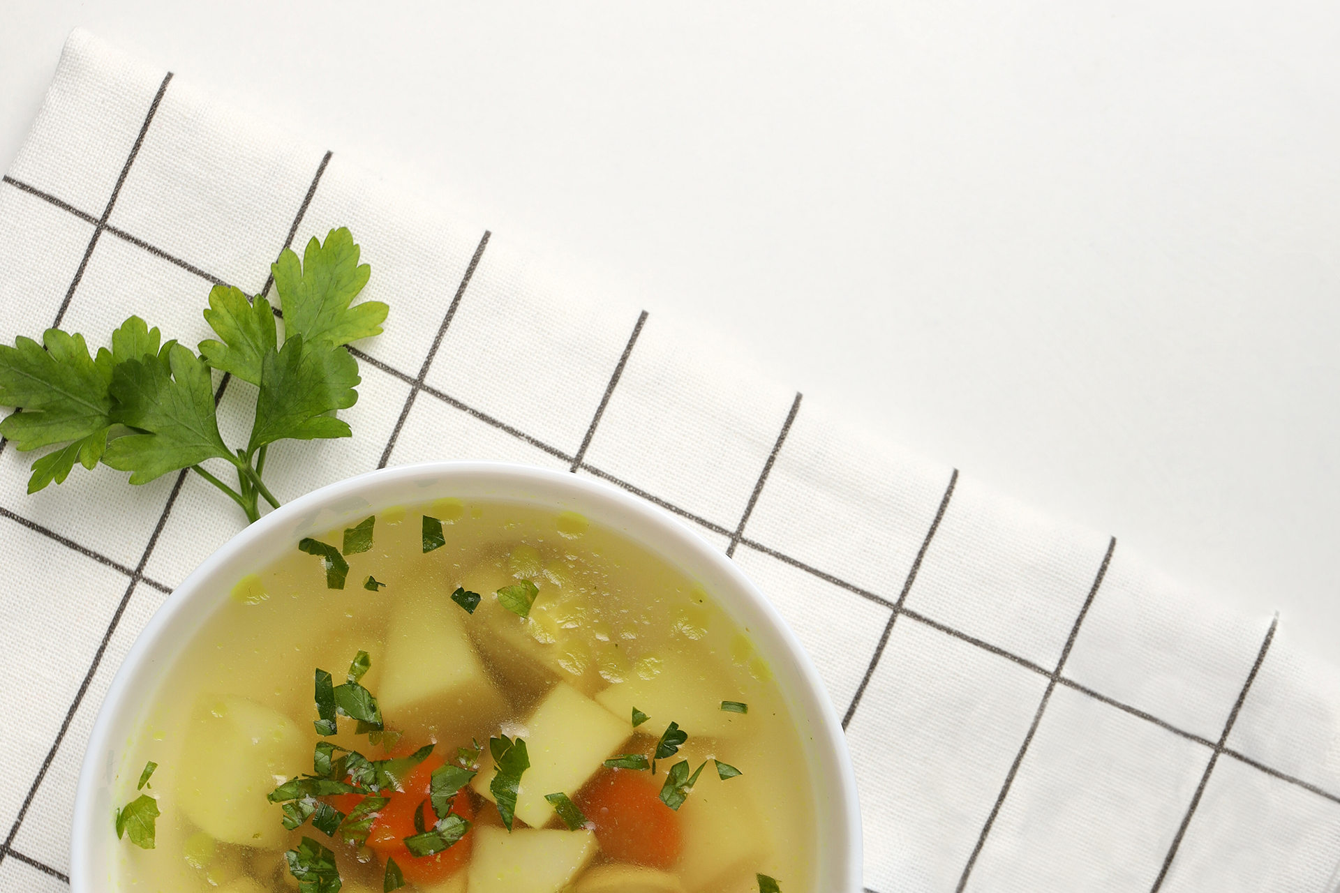 En tallrik med soppa står på en rutig kökshandduk.