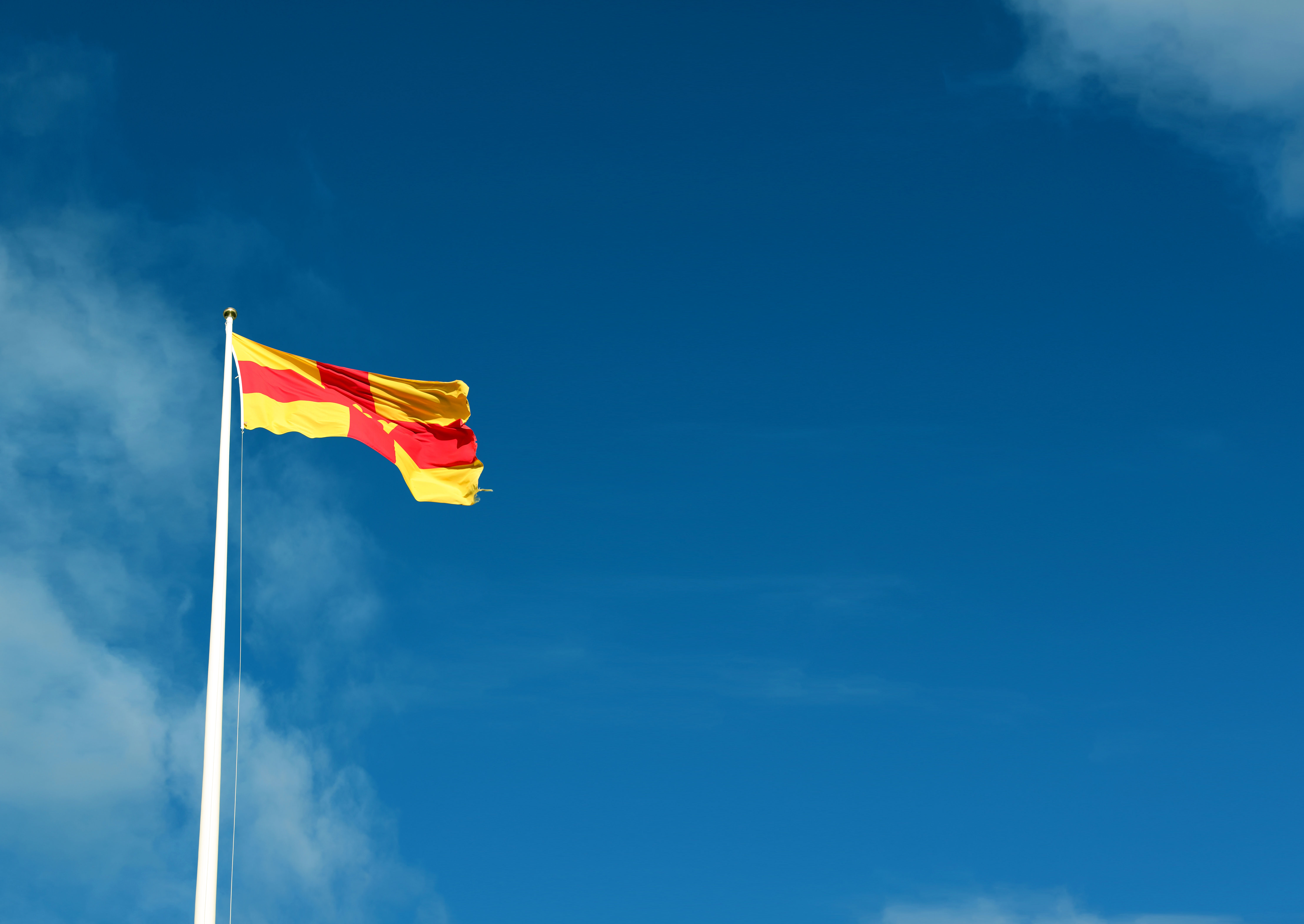 Svenska kyrkans flagga mot blå himmel.
