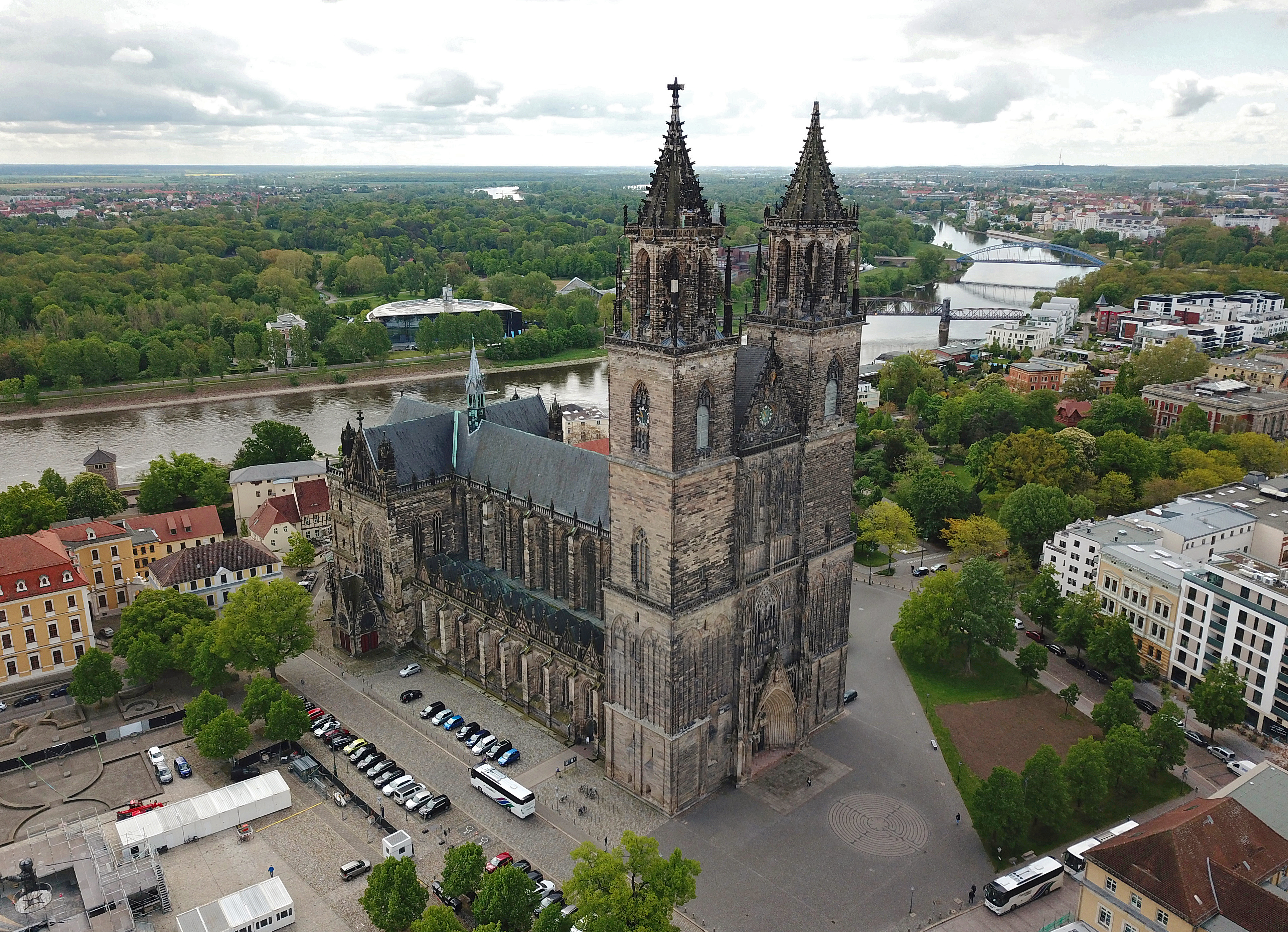 En stor domkyrka med hus, träd och bilar runt om.