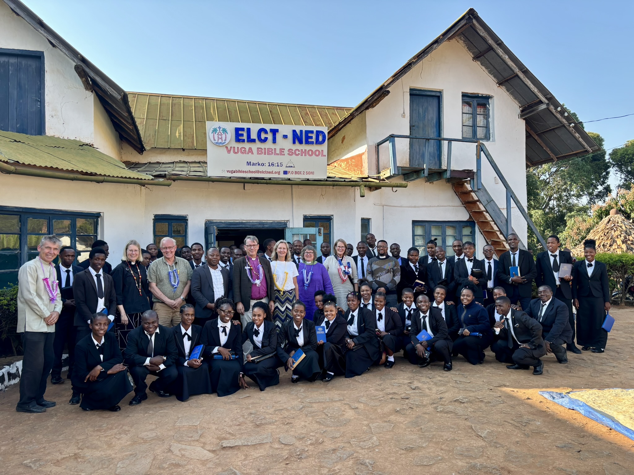 Många människor står uppställda framför ett hus.