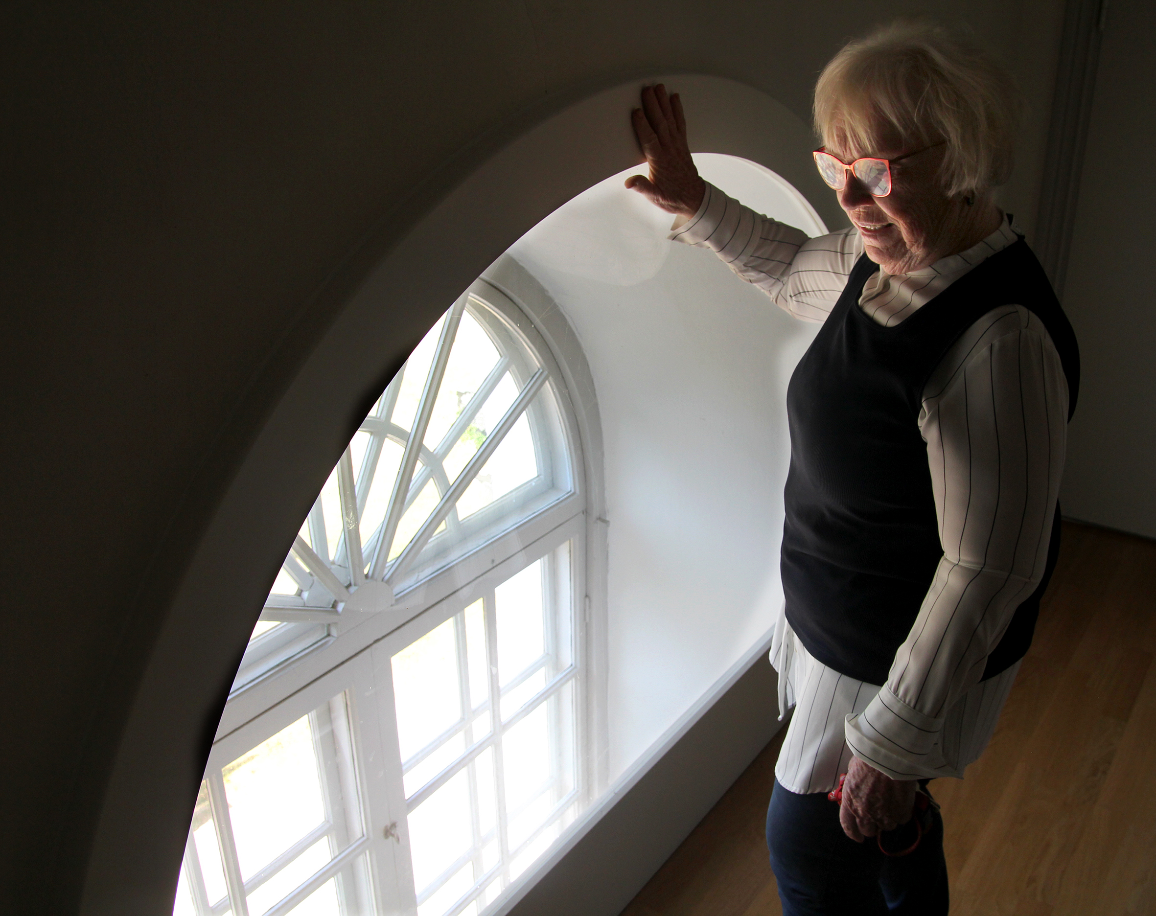 En kvinna står bredvid övre kanten på ett kyrkfönster.