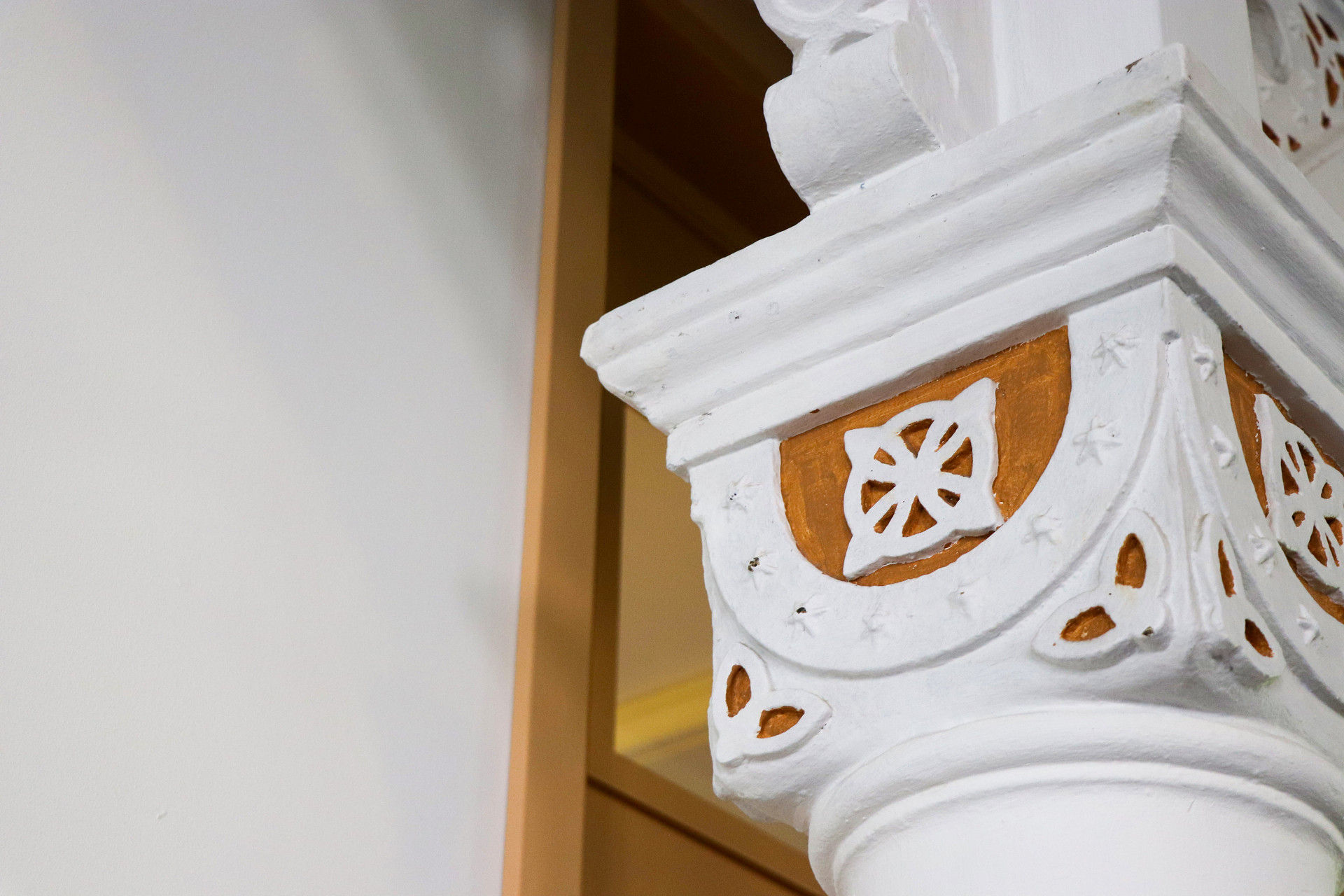 En vit pelare med ett knutmönster i toppen, mot en brun bakgrund.