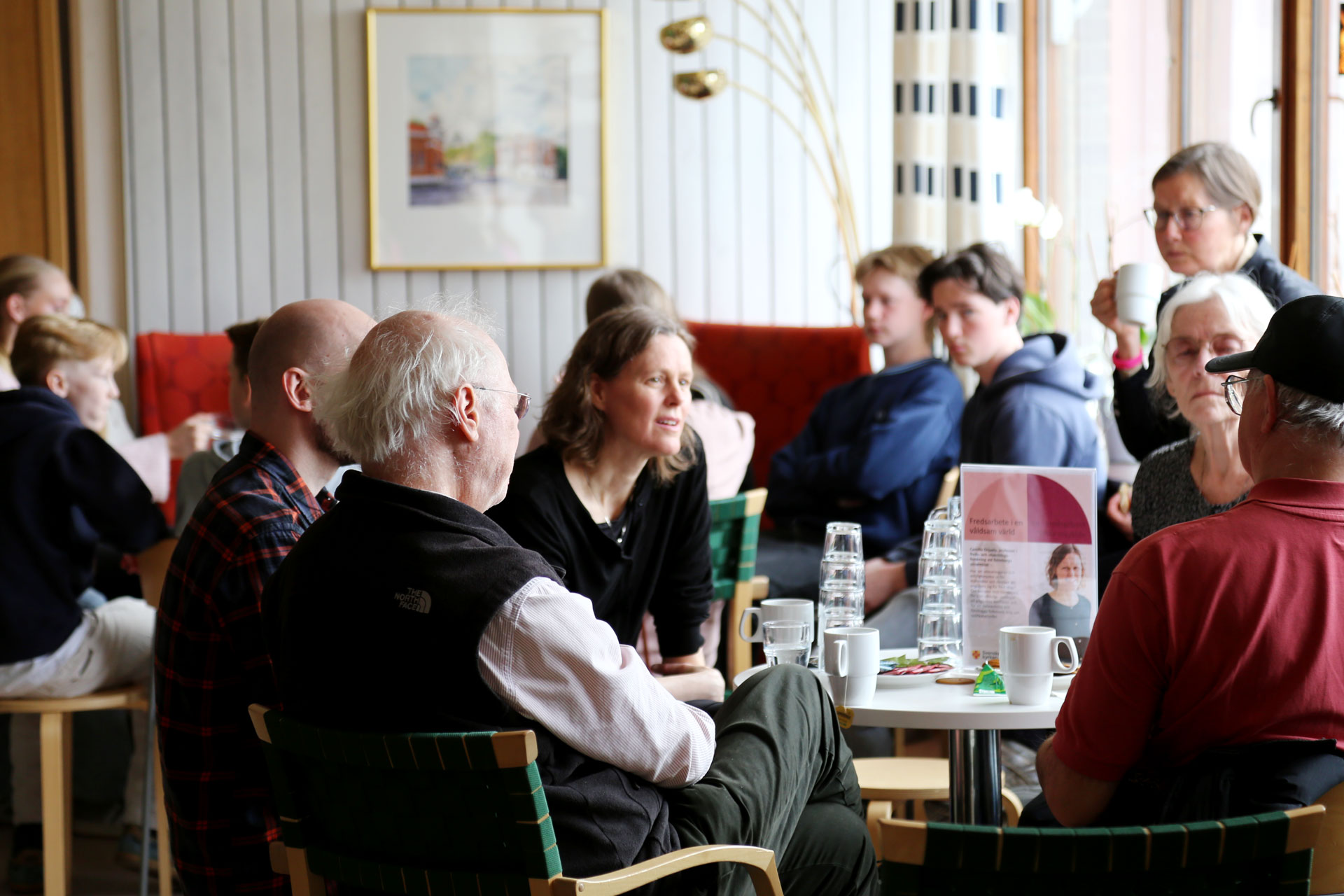 Ett rum fullt med människor i olika åldrar som är inbegripna i olika samtal.