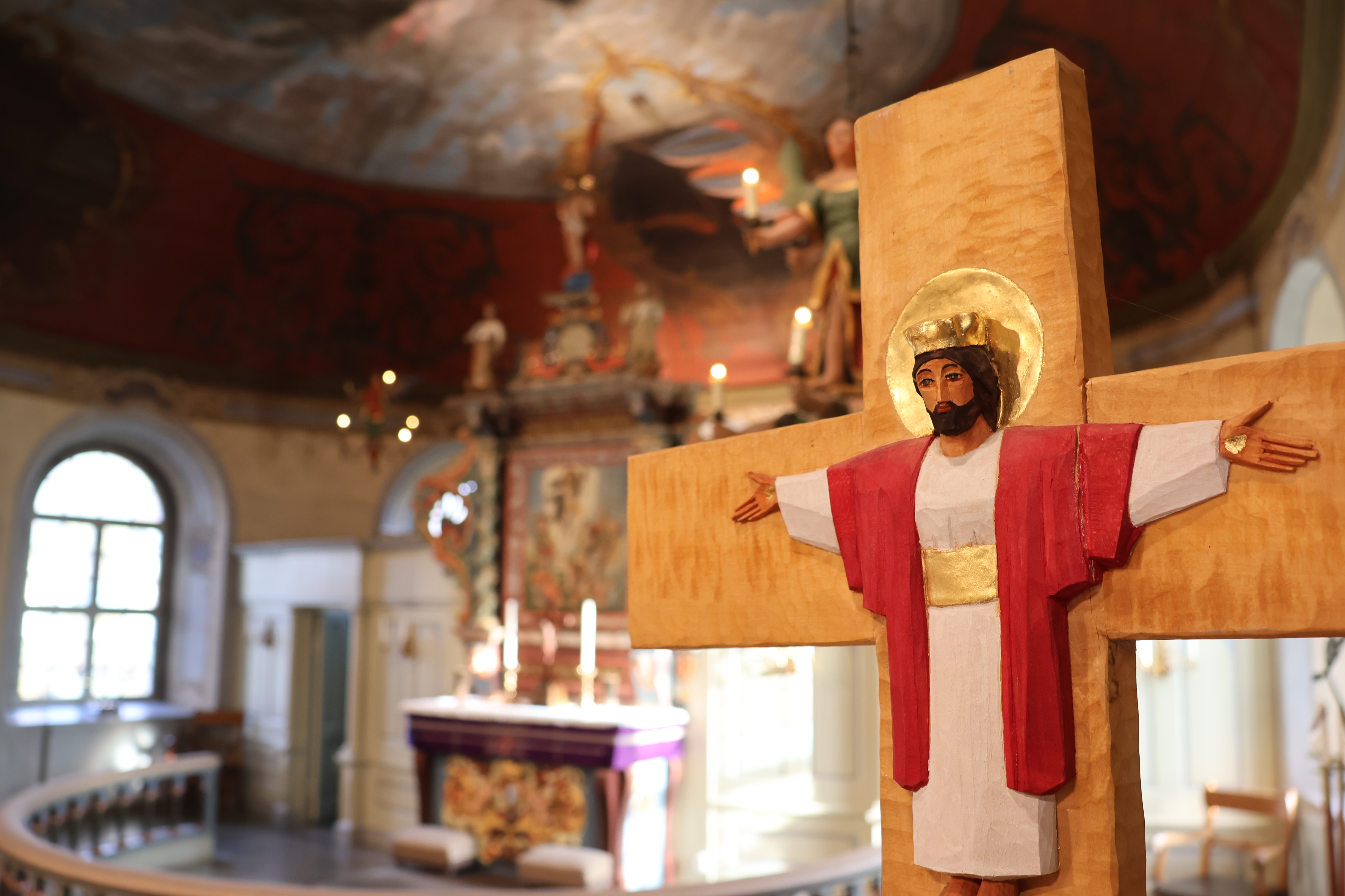 Interiör från Sätila kyrka, ett krucifix av Eva Spångberg i förgrunden, och den gamla altaruppsatsen i bakgrunden.