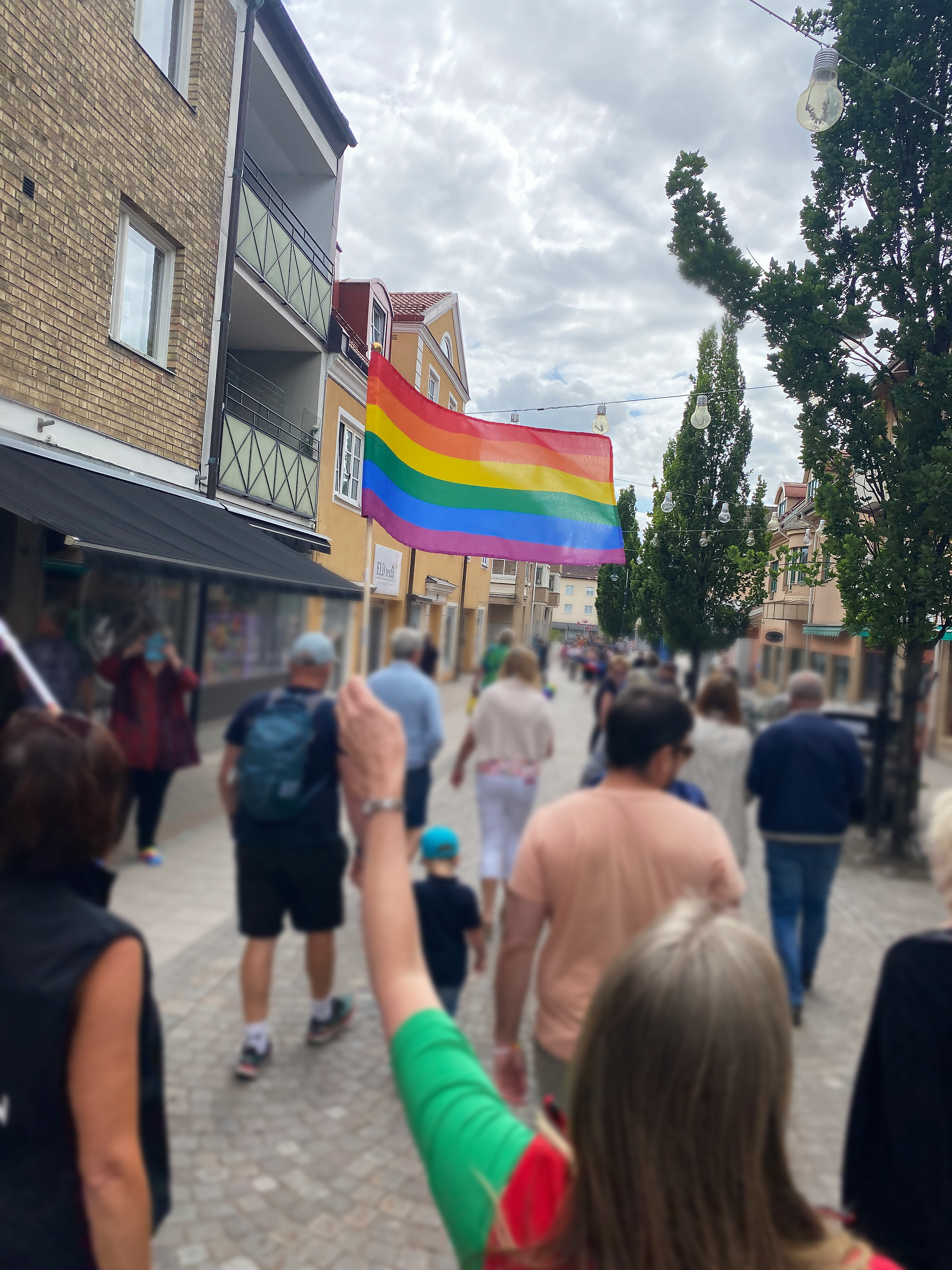 En person håller en regnbågsflagga och går i ett Pridetåg.