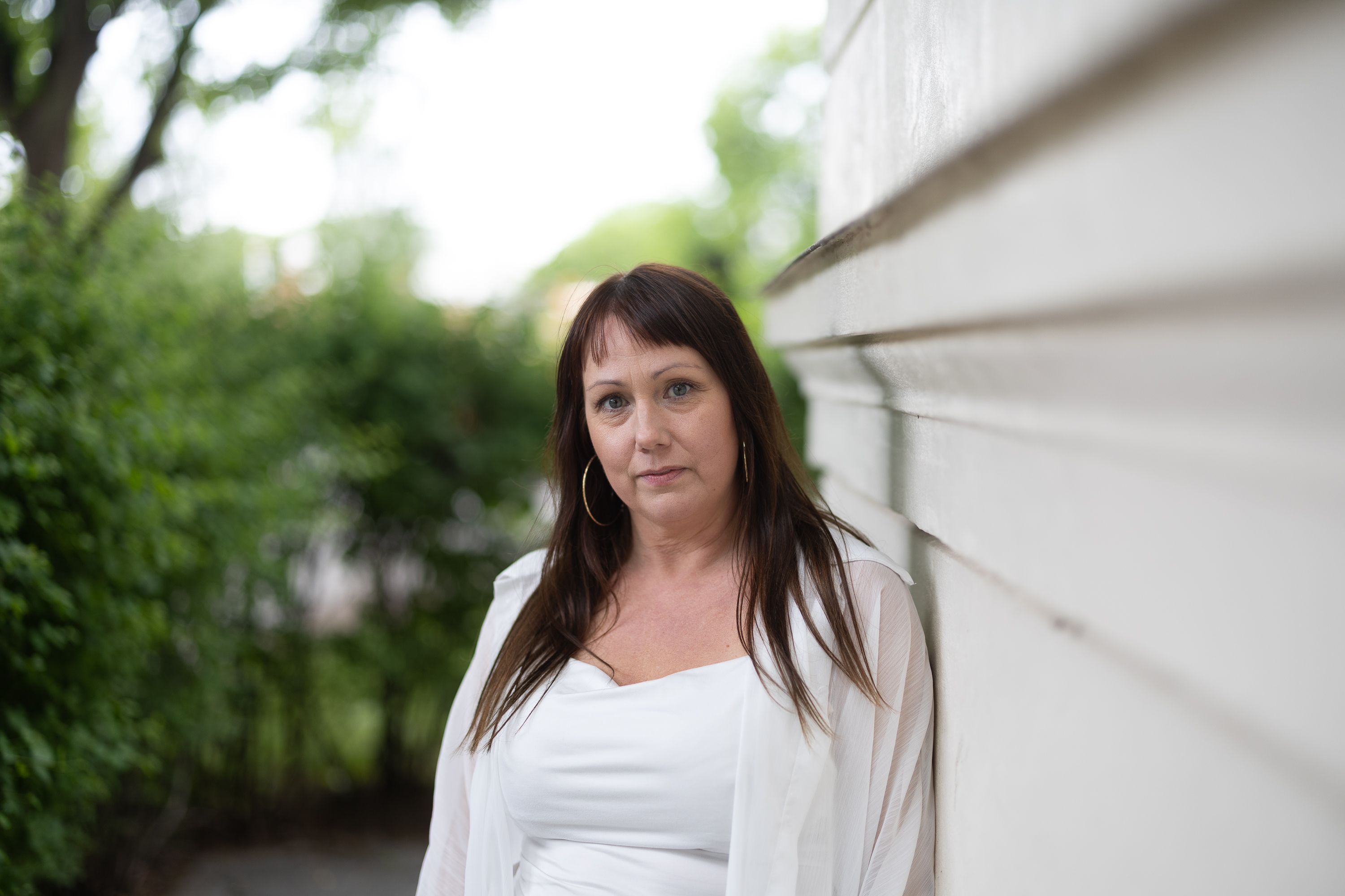 Fia Öberg i grönskan mot husvägg