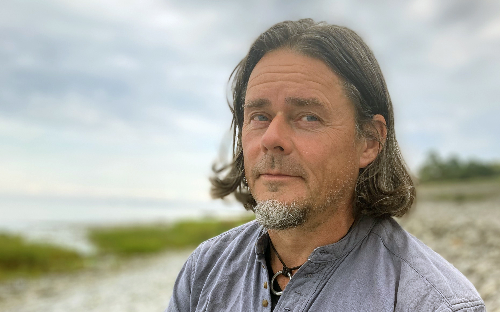 En man står med strand och vatten i bakgrunden, bilden är från Gotland.