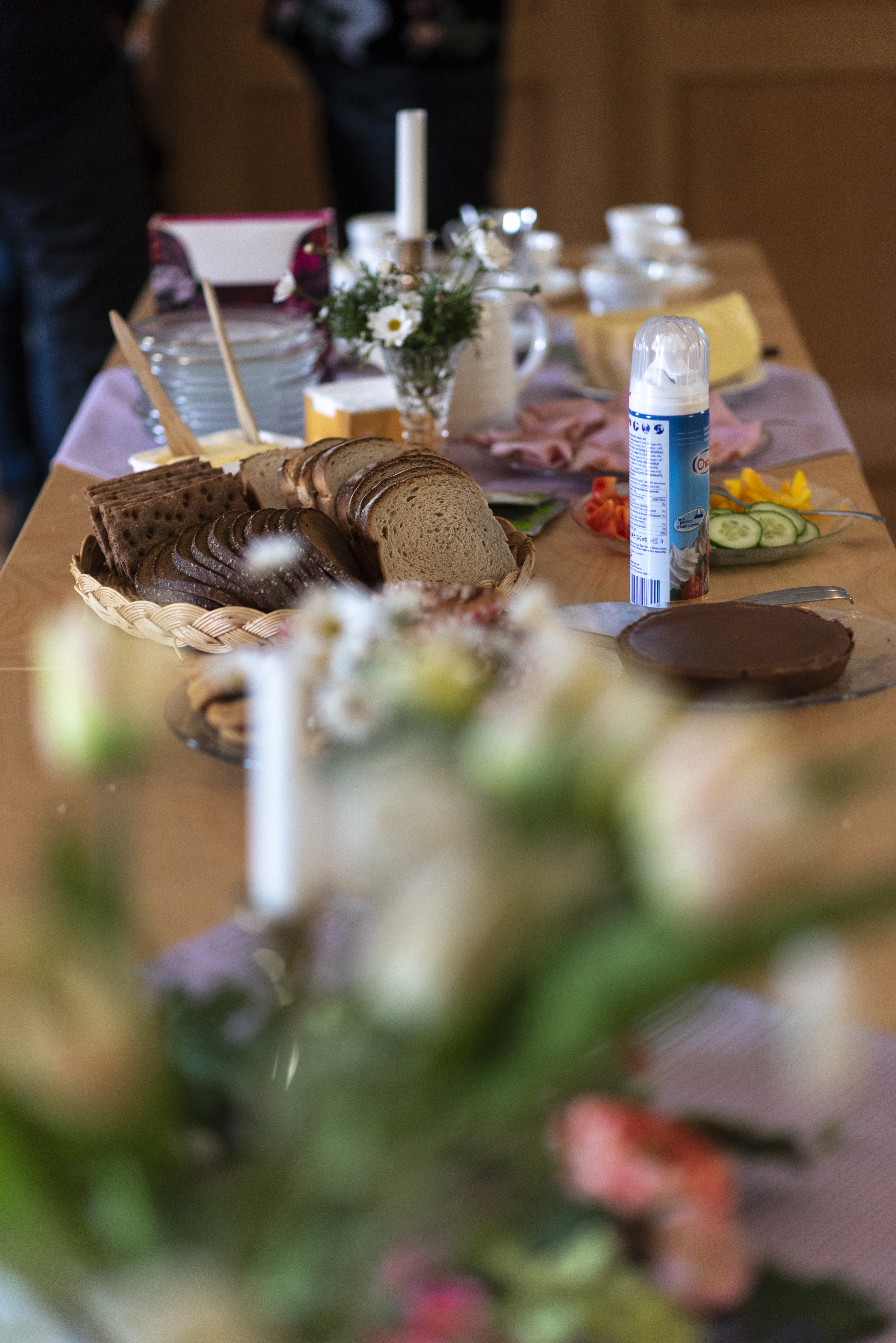 I bild syns ett uppdukat bord med bröd, smör, porslin och fika.