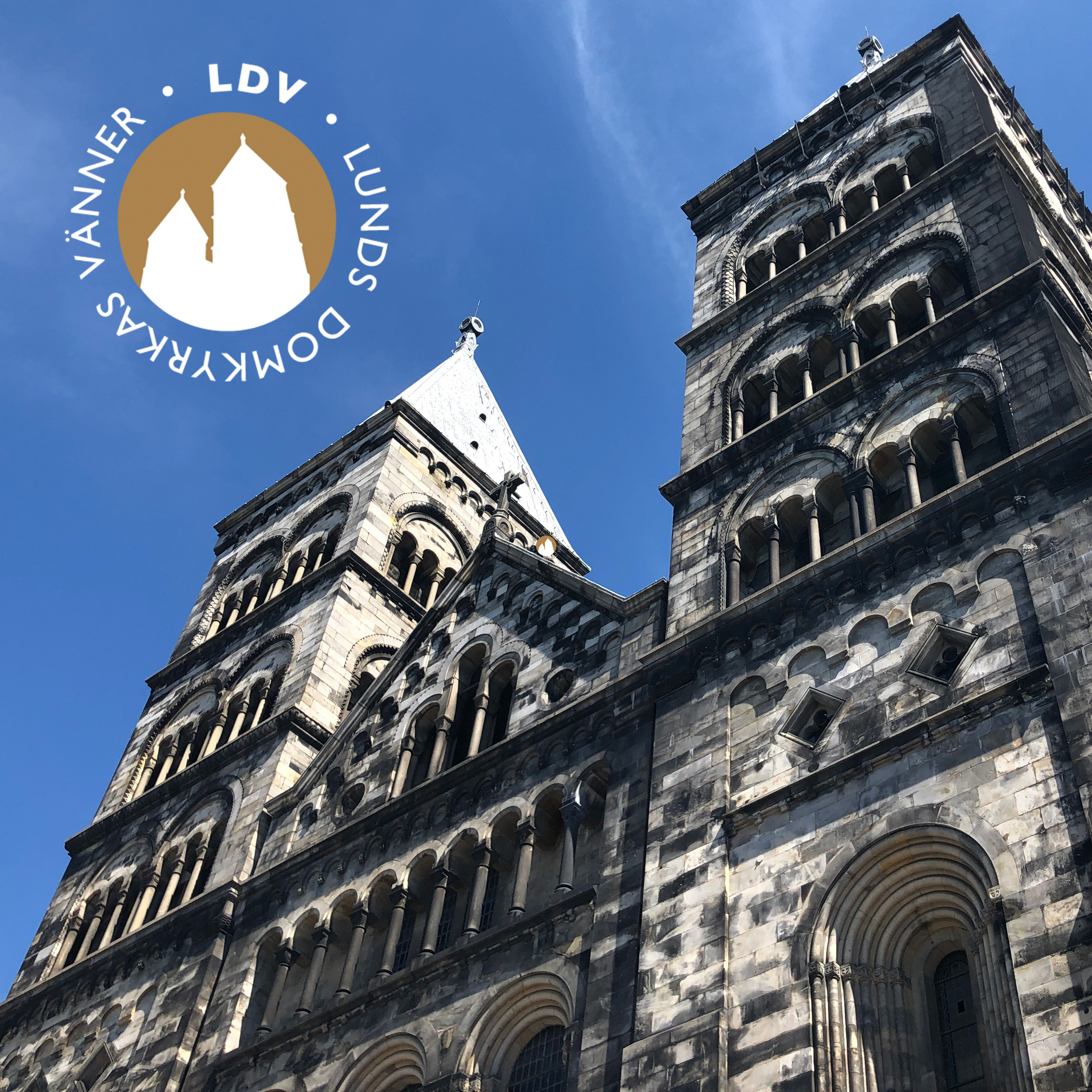 Domkyrkans torn mot blå himmel och med Lunds domkyrkas vänner logotyp,