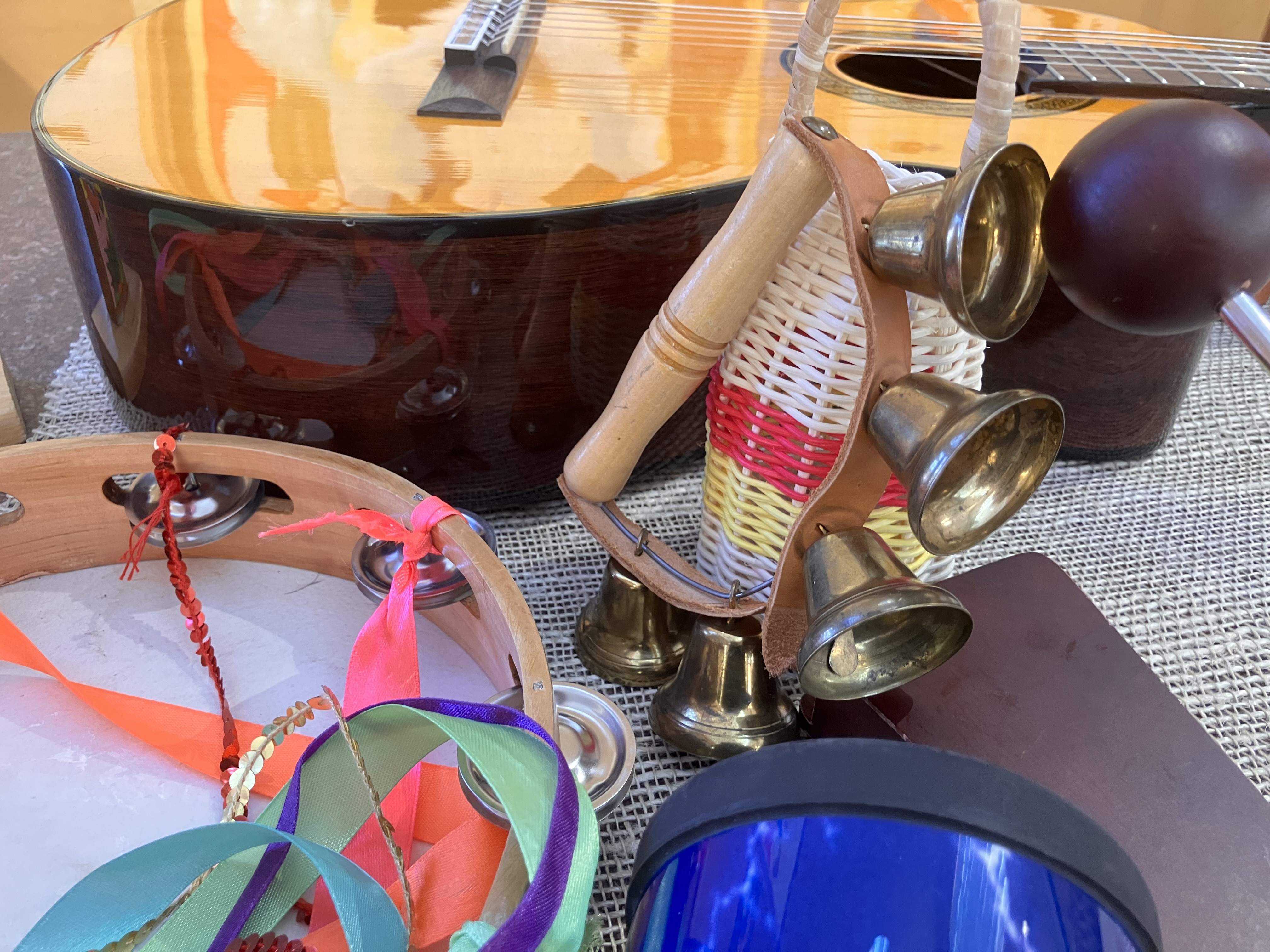 En gitarr syns i övre delen av bilden, En tamburin med färgade band ligger framför. 