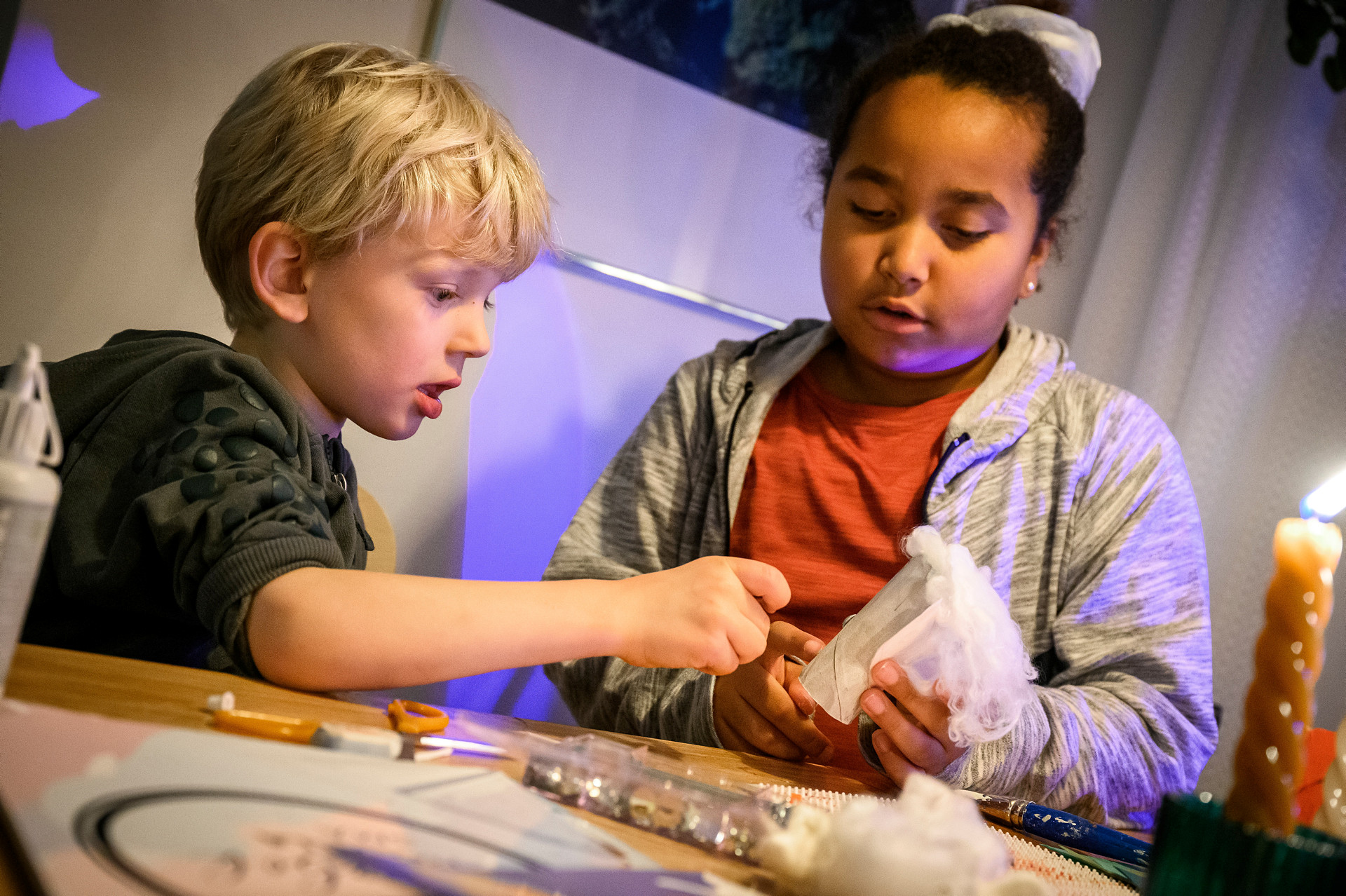 Två barn i lågstadieålder vid ett bord med pysselmaterial.