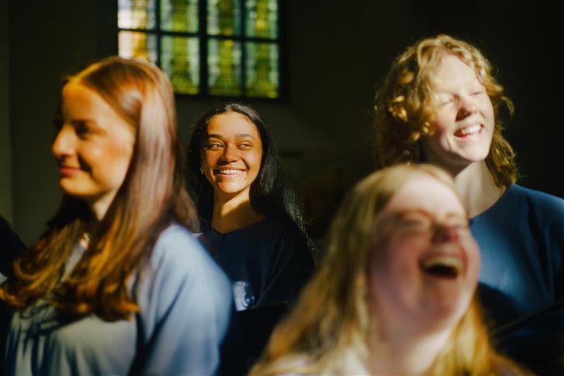 Unga tjejer sjunger i kör och har roligt, ser glada ut.