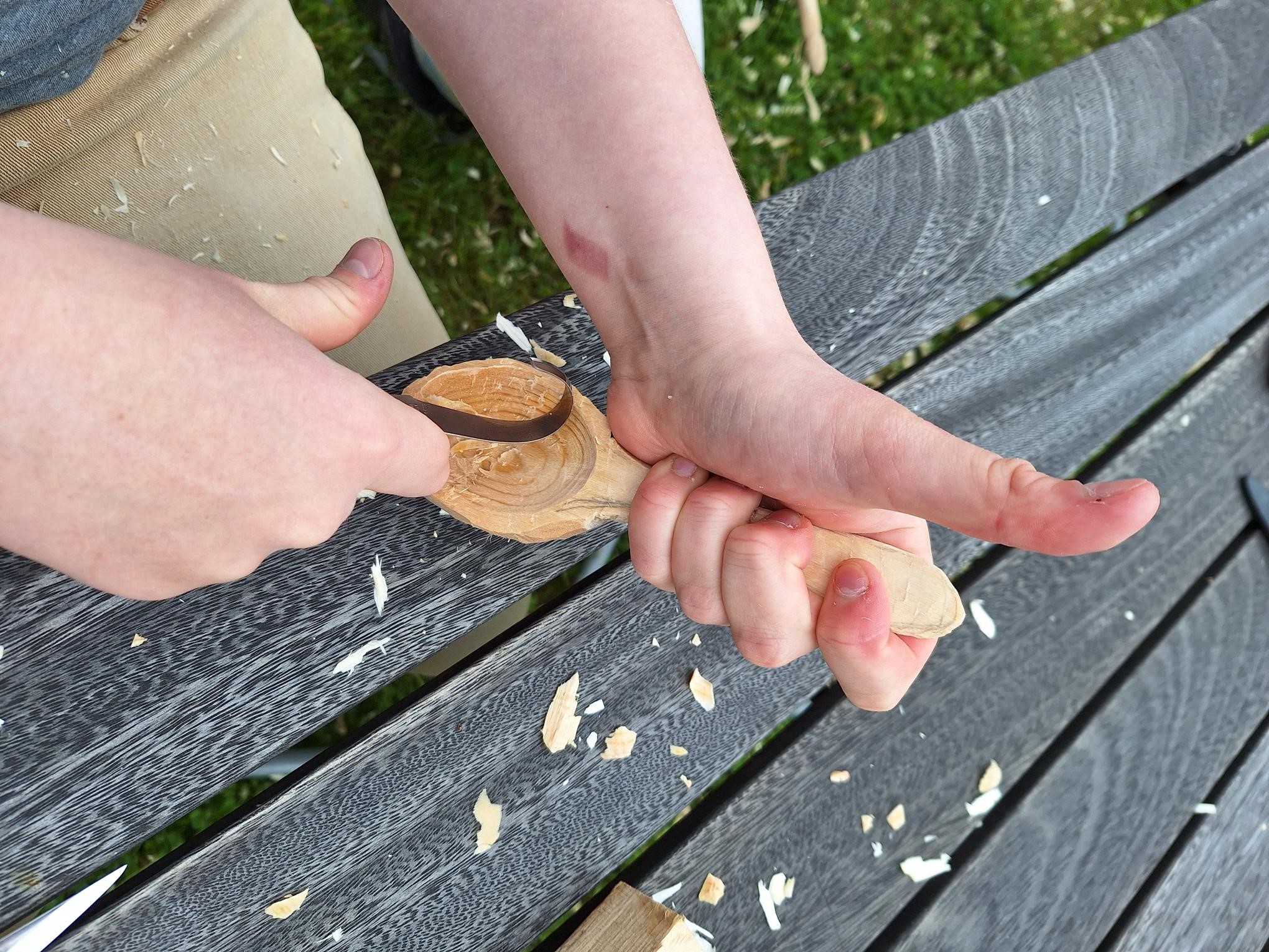Närbild på två händer som karvar en träsked