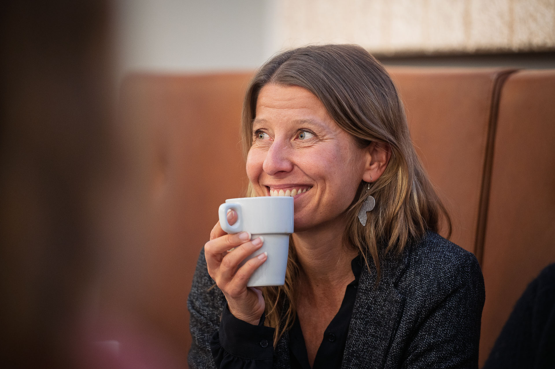 Kvinna som lyssnar till ett samtal och håller en kaffekopp i handen.
