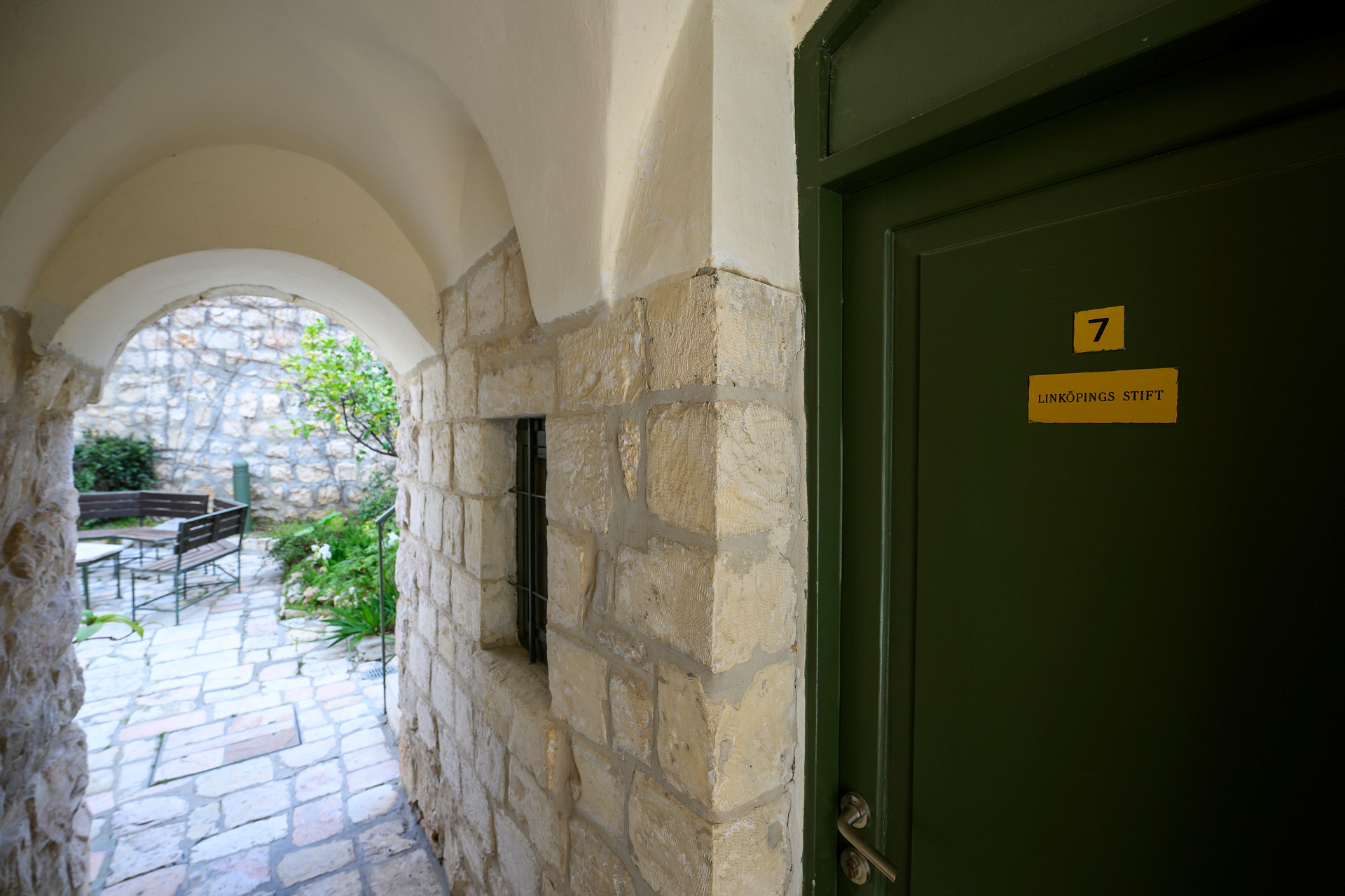 En grön dörr i trång passage.