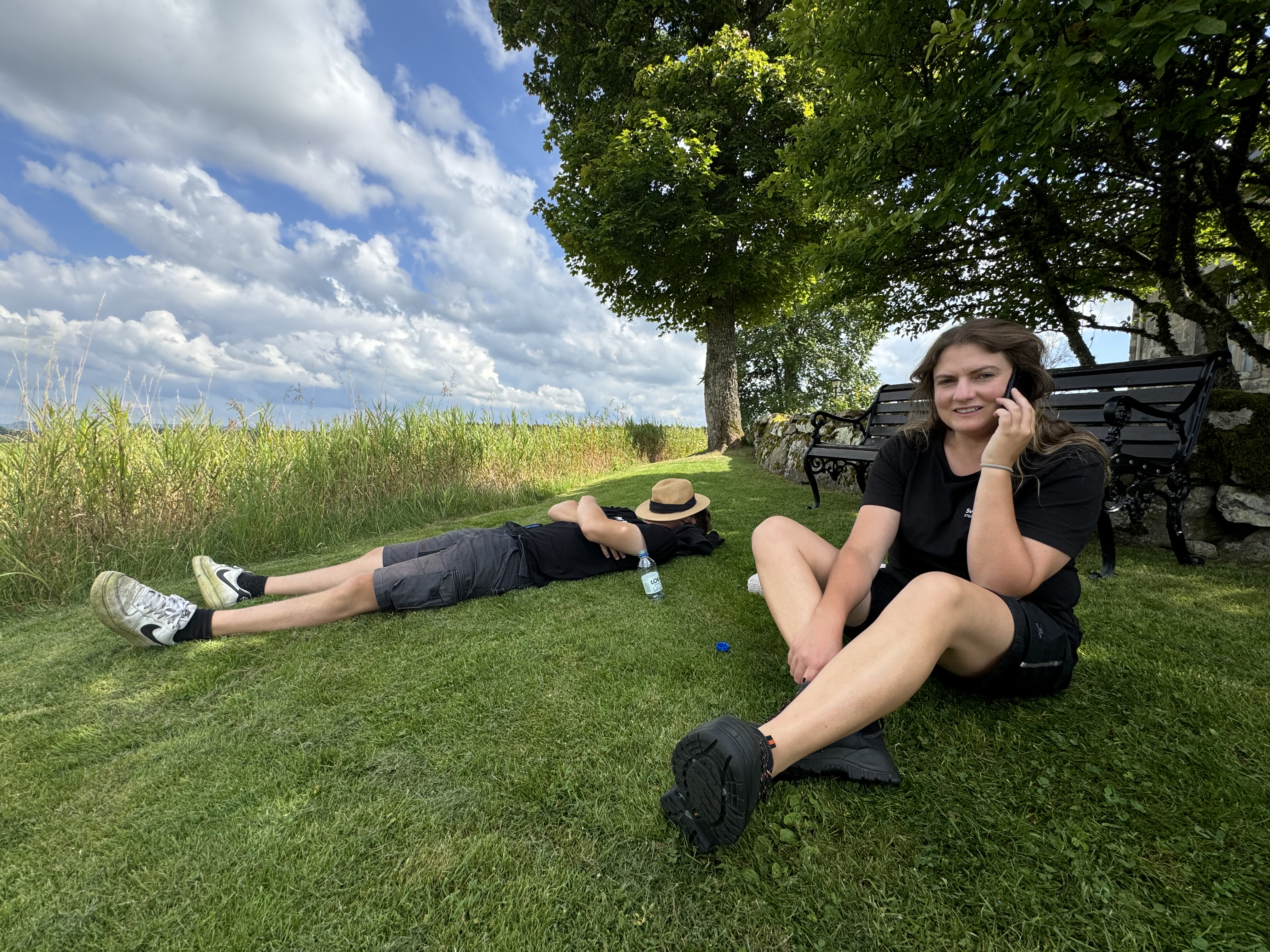 En man ligger i gräset och en kvinna sitter bredvid