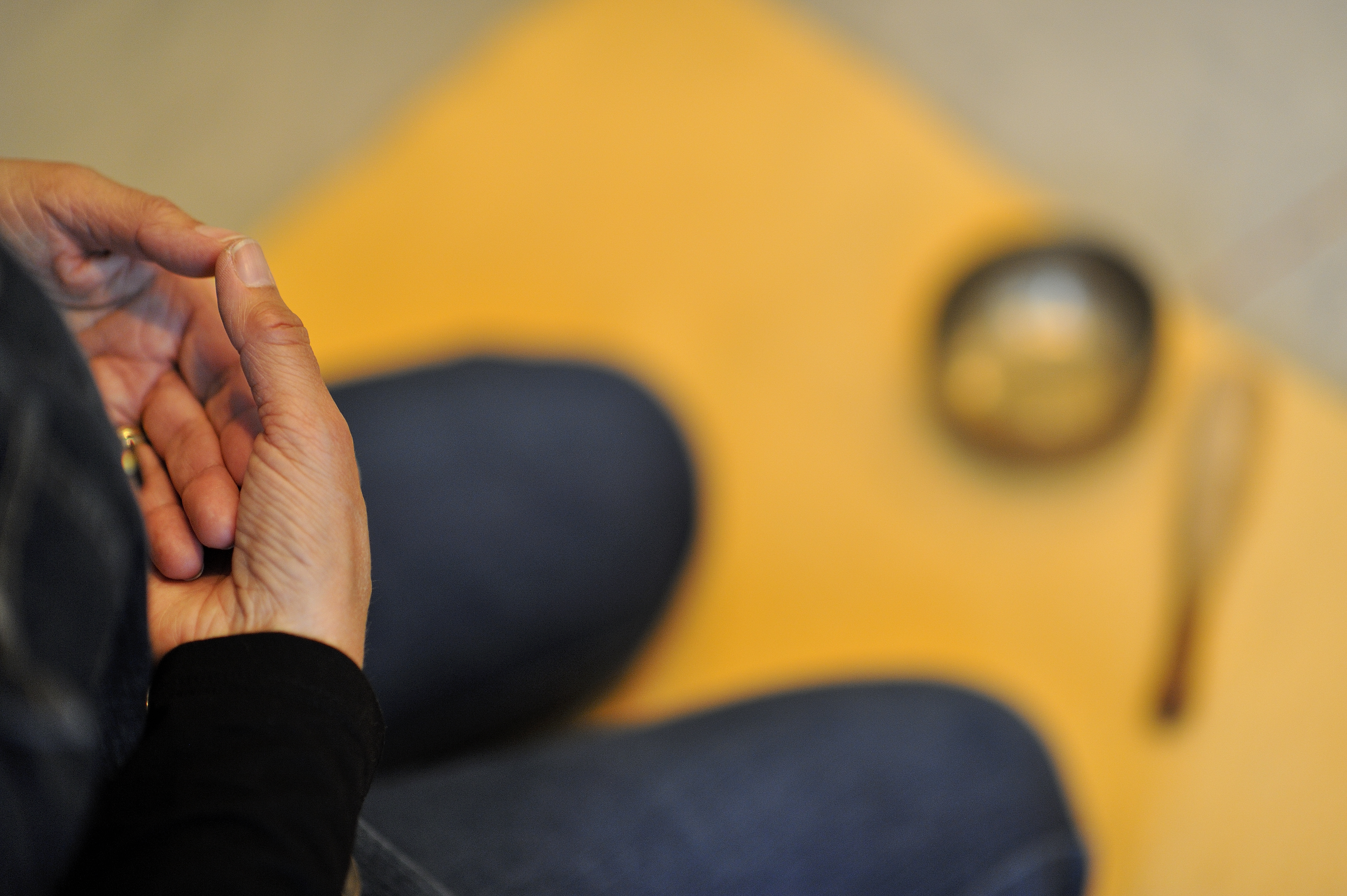 Kvinna sitter och mediterar på gul yogamatta.