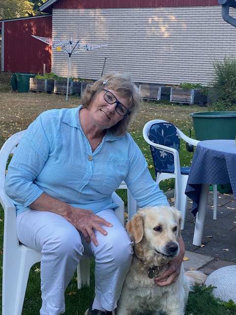 Kvinna sitter vid ett bord ute med sin hund.