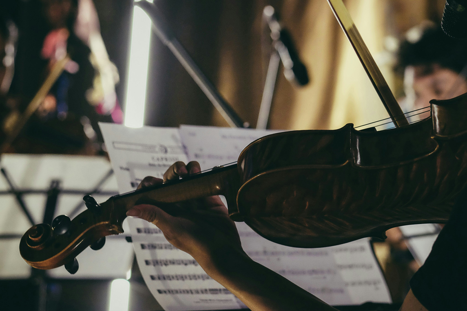 Poetiskt foto på en fiol framför ett notställ med notblad.