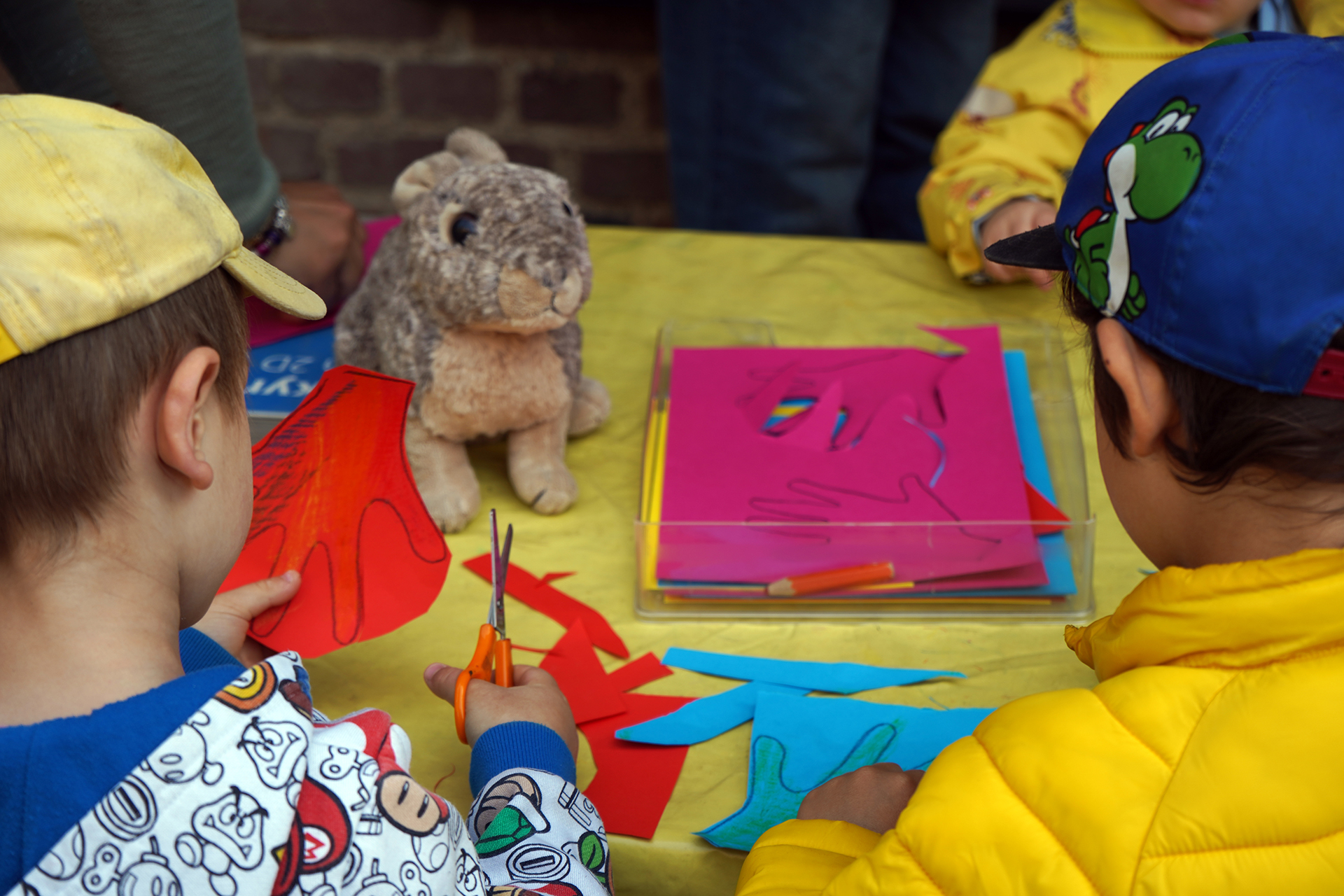 Två förskolebarn pysslar vid ett bord utomhus på Vildrosens förskolas gård.