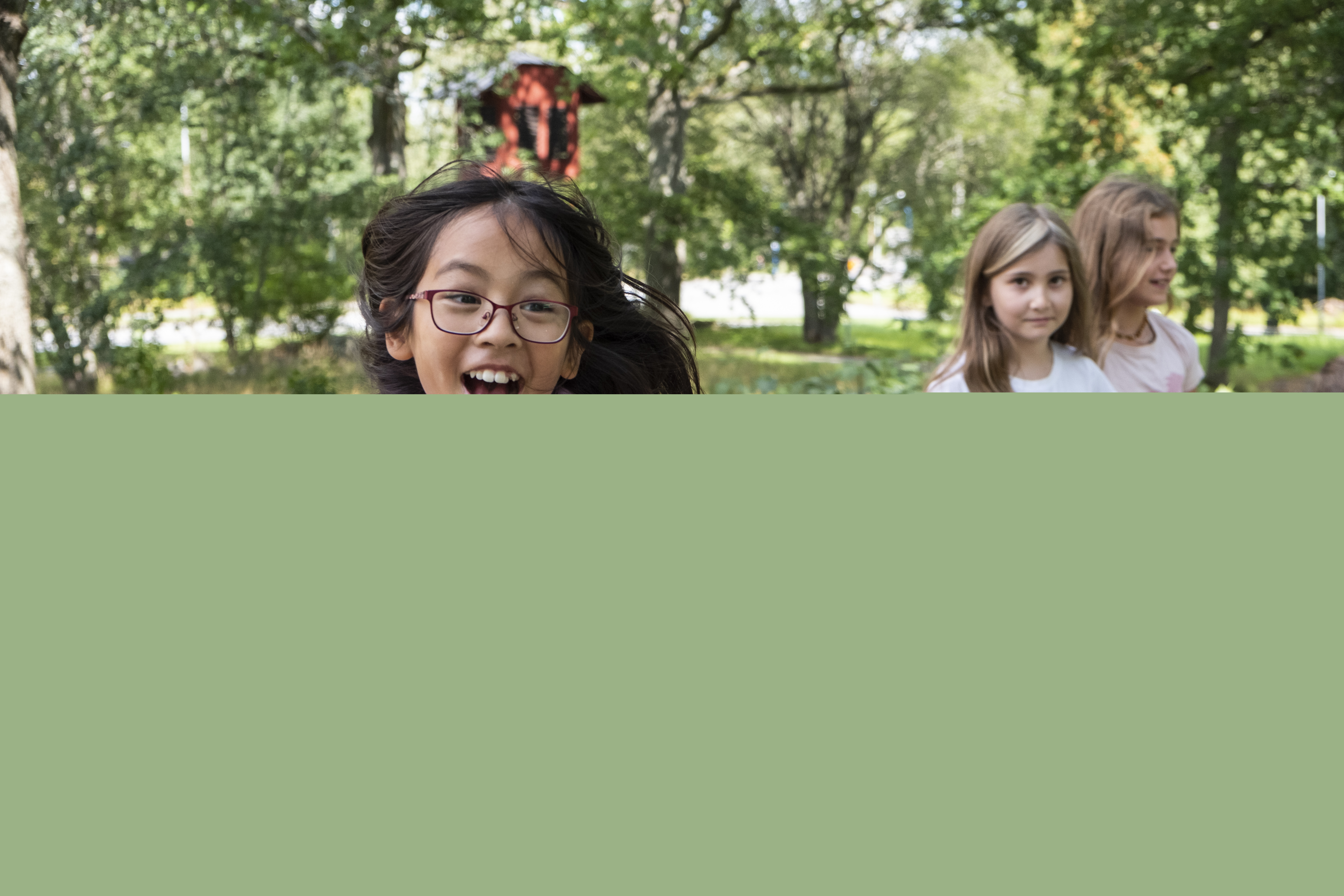 Flicka med glasögon och lila tröja springer mot kameran